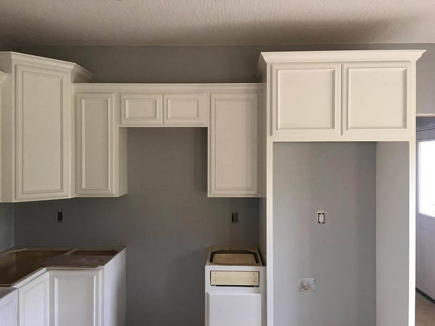 White kitchen with shaker-style cabinets, stainless steel appliances, light stone countertops, and a black accent border along the wall.