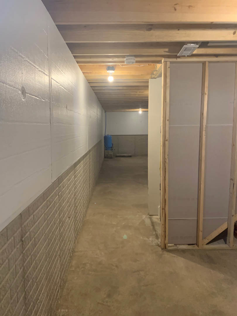 Hallway featuring exposed brick wall, white plaster wall, and wood framing with light-colored flooring