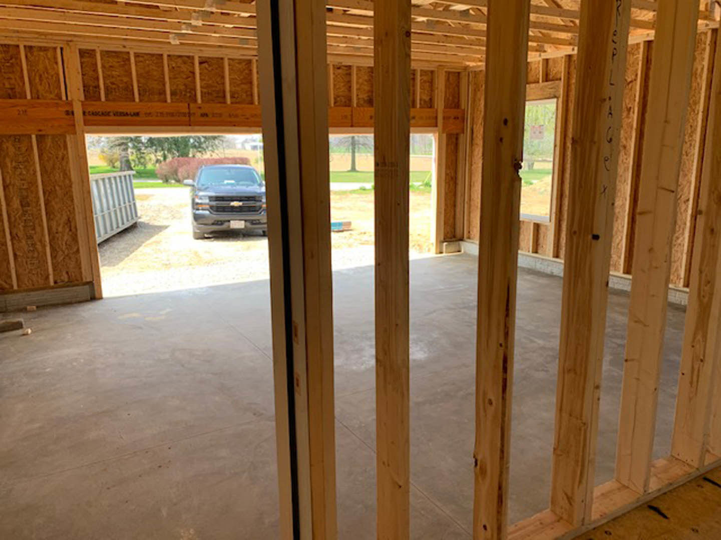 Silver sedan parked on light wood plank garage floor, white paneled garage door partially visible, clean interior with minimal decor