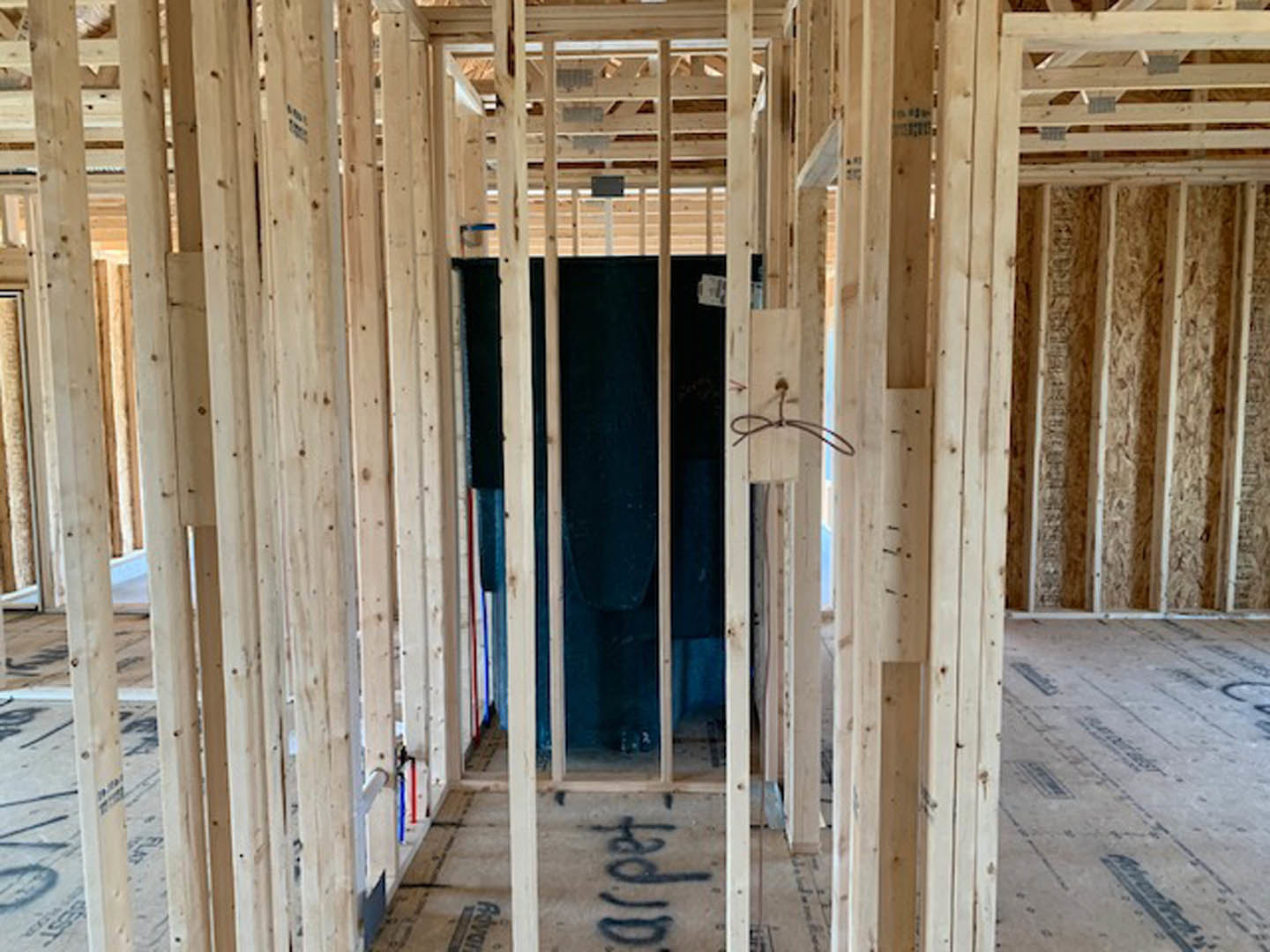 Exposed wood framing with beams and planks, unfinished interior walls, visible insulation, close-up of lumber surfaces and construction details