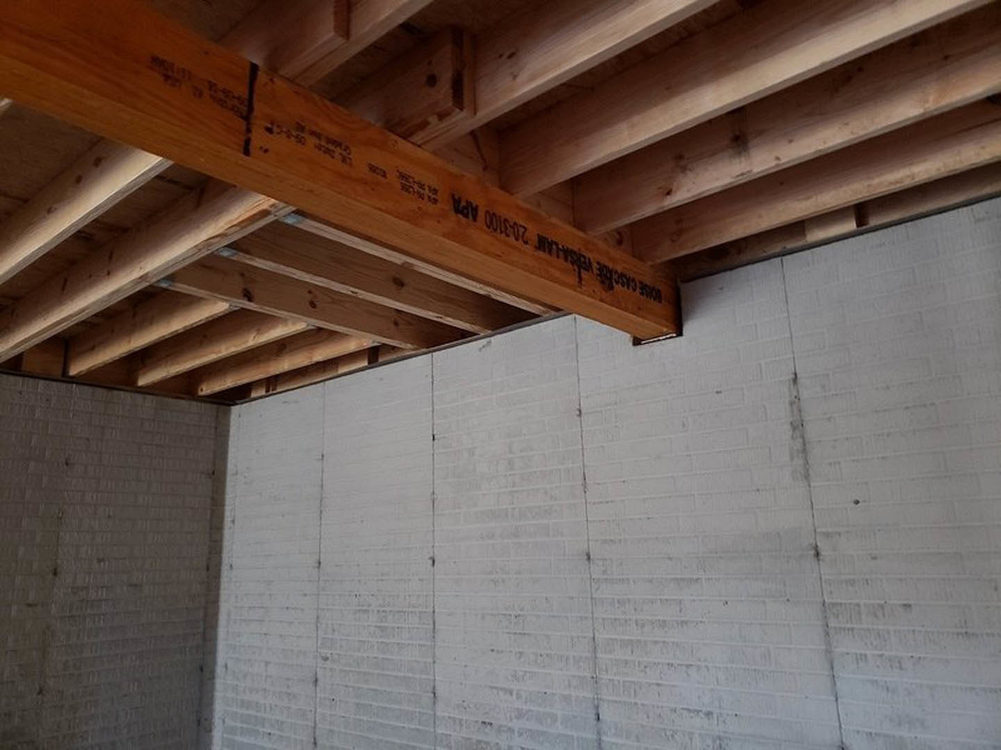 Exposed wooden ceiling beams above a white painted brick wall in a modern interior room