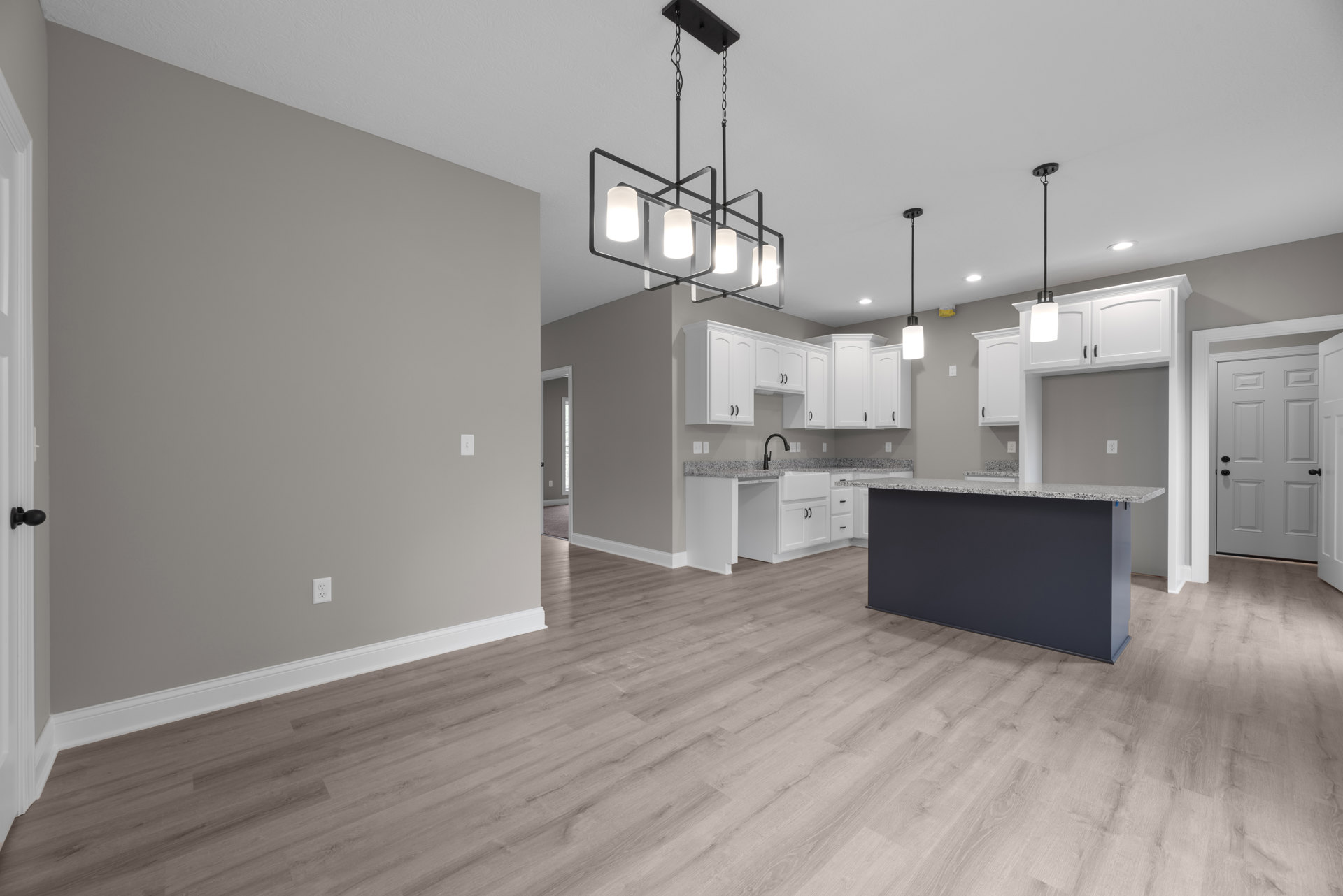 Open kitchen and dining area featuring white shaker cabinets, black hardware, hardwood floors, white doors, and recessed lighting.