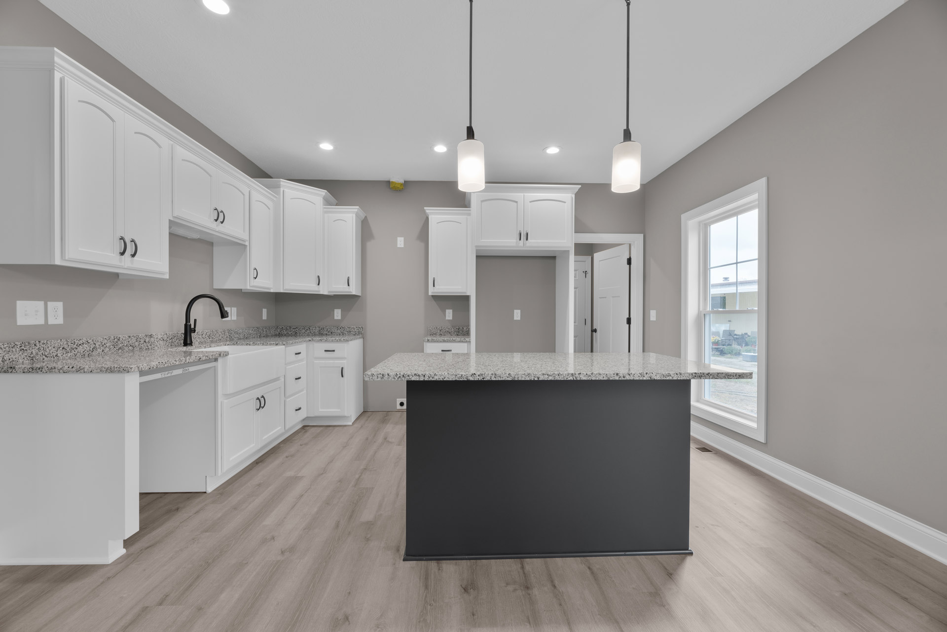 Modern kitchen featuring black and white countertop, black faucet, white rectangular pendant light, light switch on wall, and sleek cabinetry.