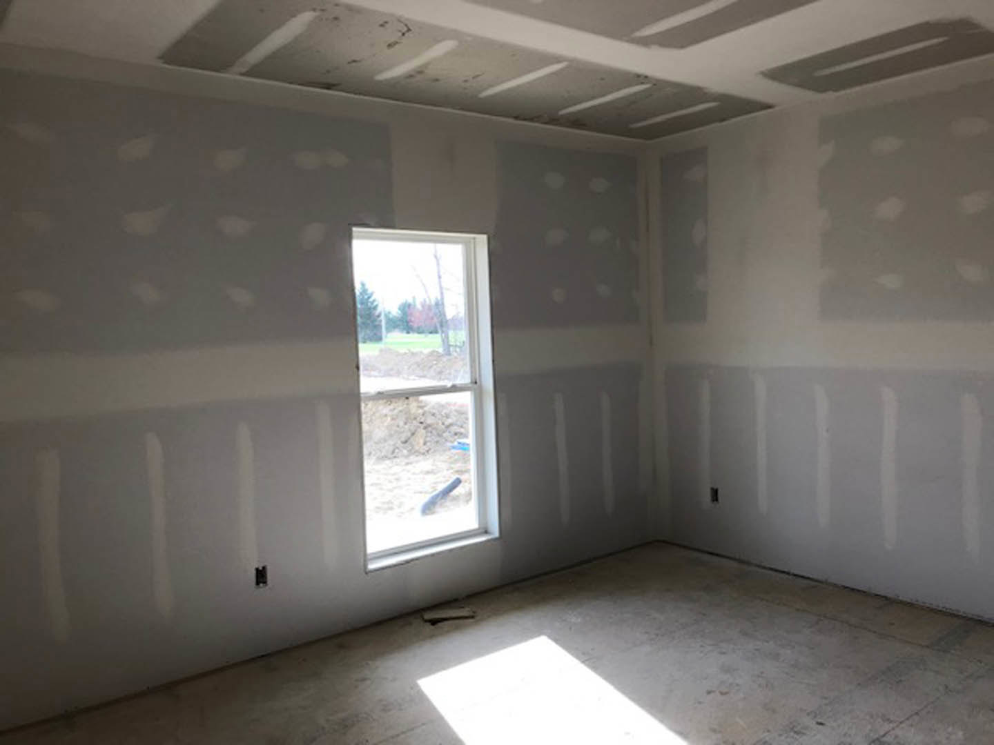 Bright room with two large windows, white painted walls, light wood flooring, sunlight streaming onto the floor, and smooth plaster ceiling.