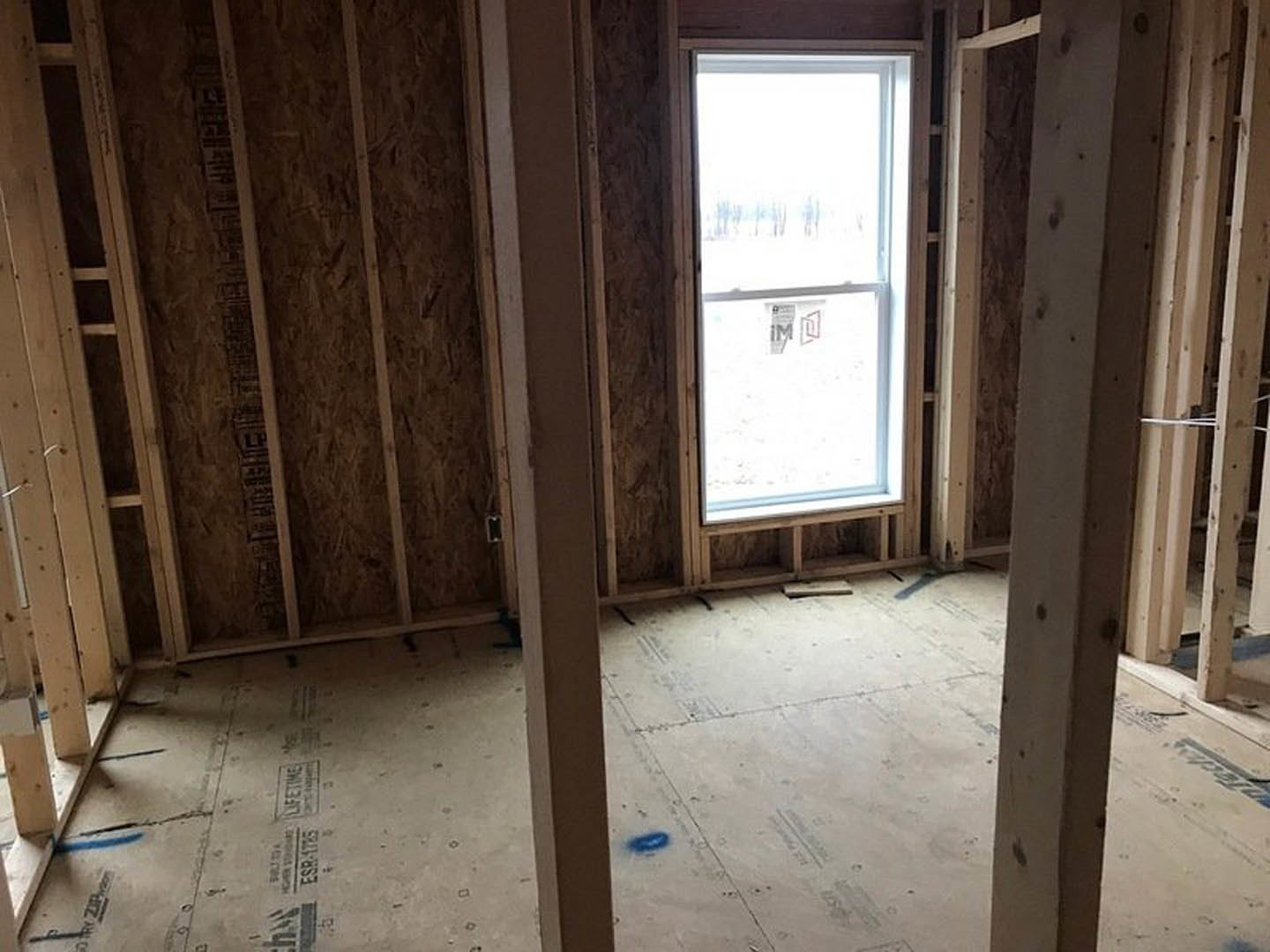 Wood-paneled room with large window, exposed beams, and blue accent on floor