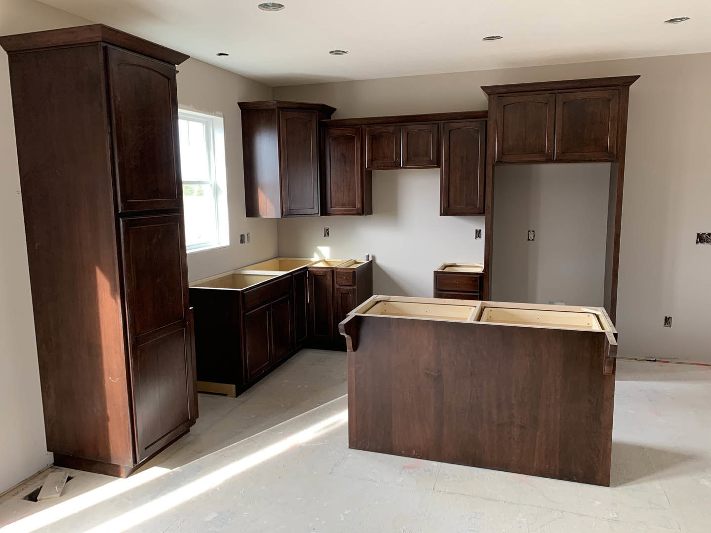 Kitchen featuring dark wood cabinets, white walls, stone countertops, and a large window above the sink.