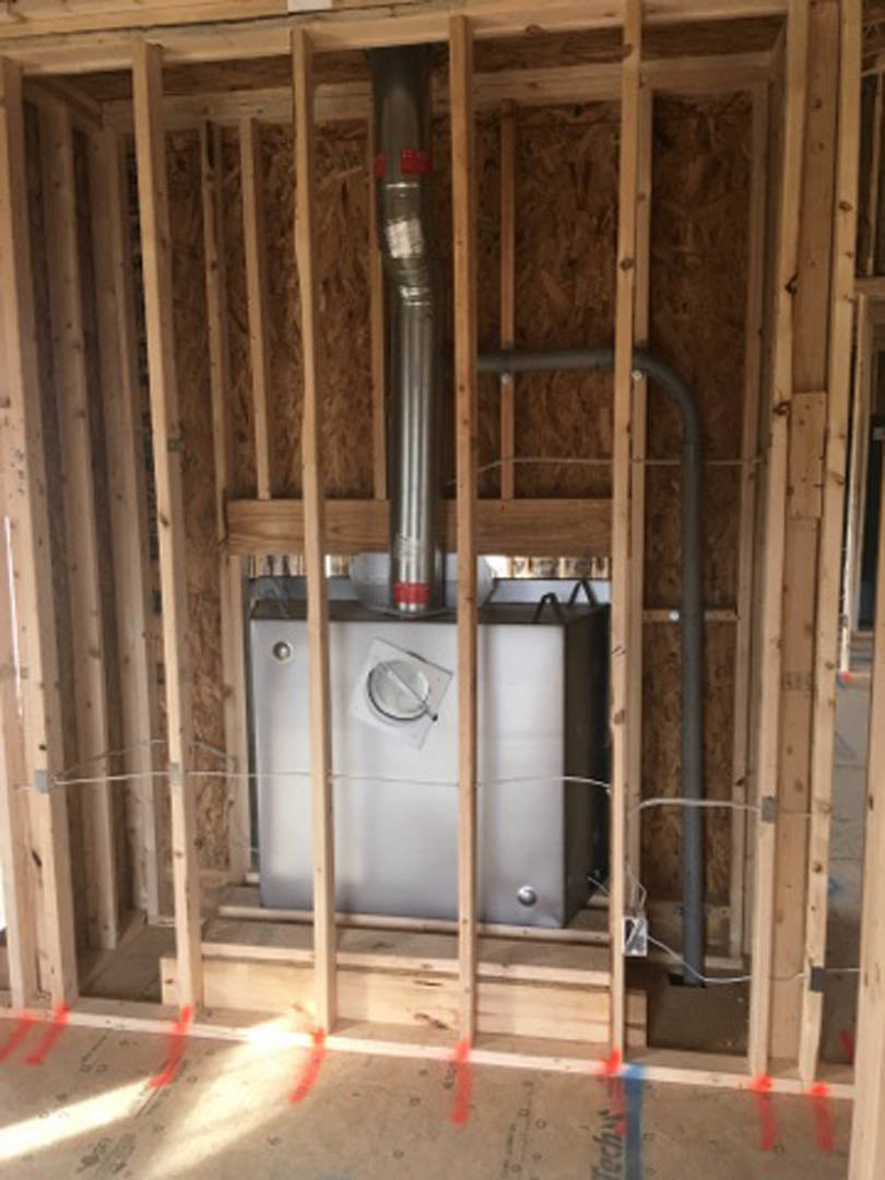 Exposed metal utility box set within unfinished wood framing, surrounded by construction materials and insulation in a residential interior remodel.
