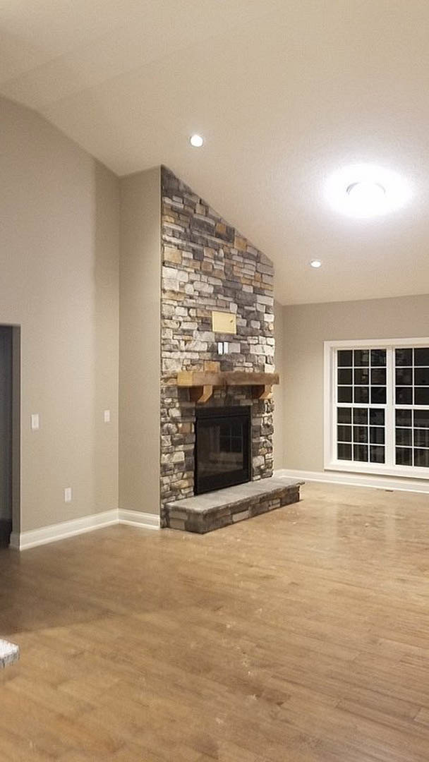 Stone fireplace with raised hearth, hardwood floors, square window, and neutral walls in a modern living room
