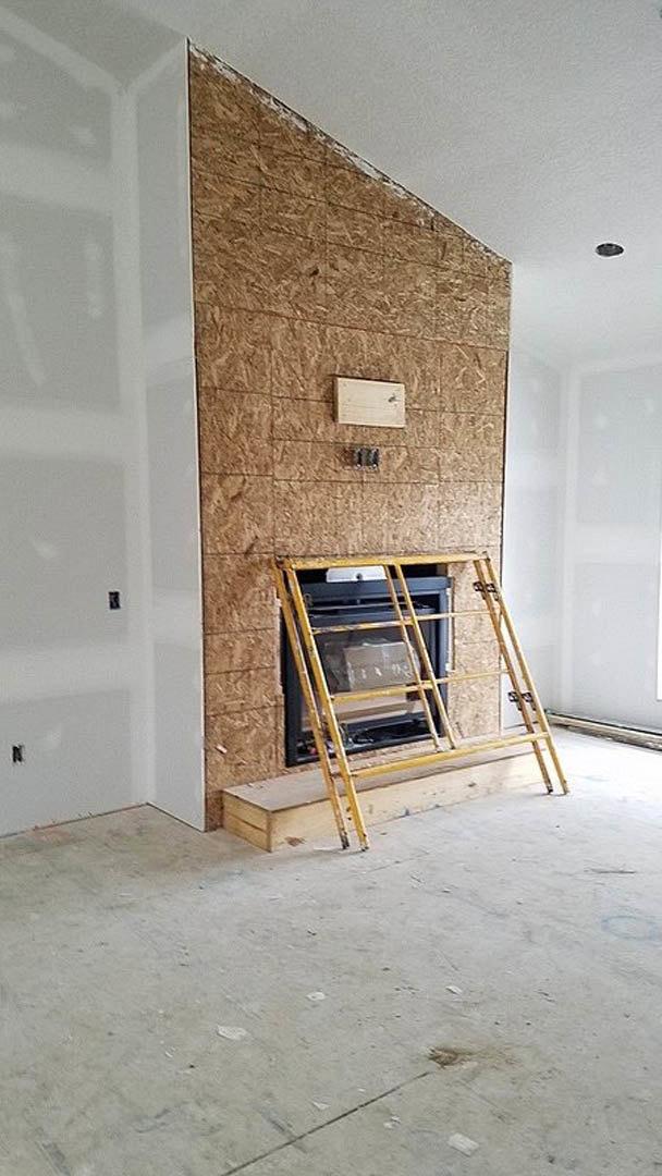 Wooden ladder leaning against a plaster fireplace in a modern indoor living space with composite flooring