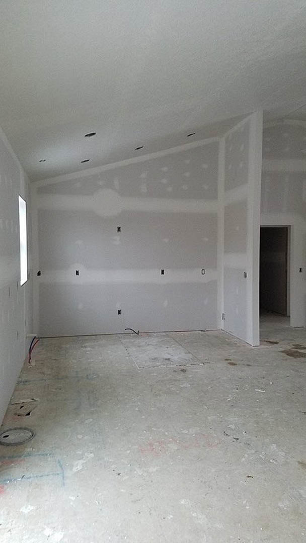 Empty room with smooth white plaster walls, large window, light-colored floor, and plain ceiling.