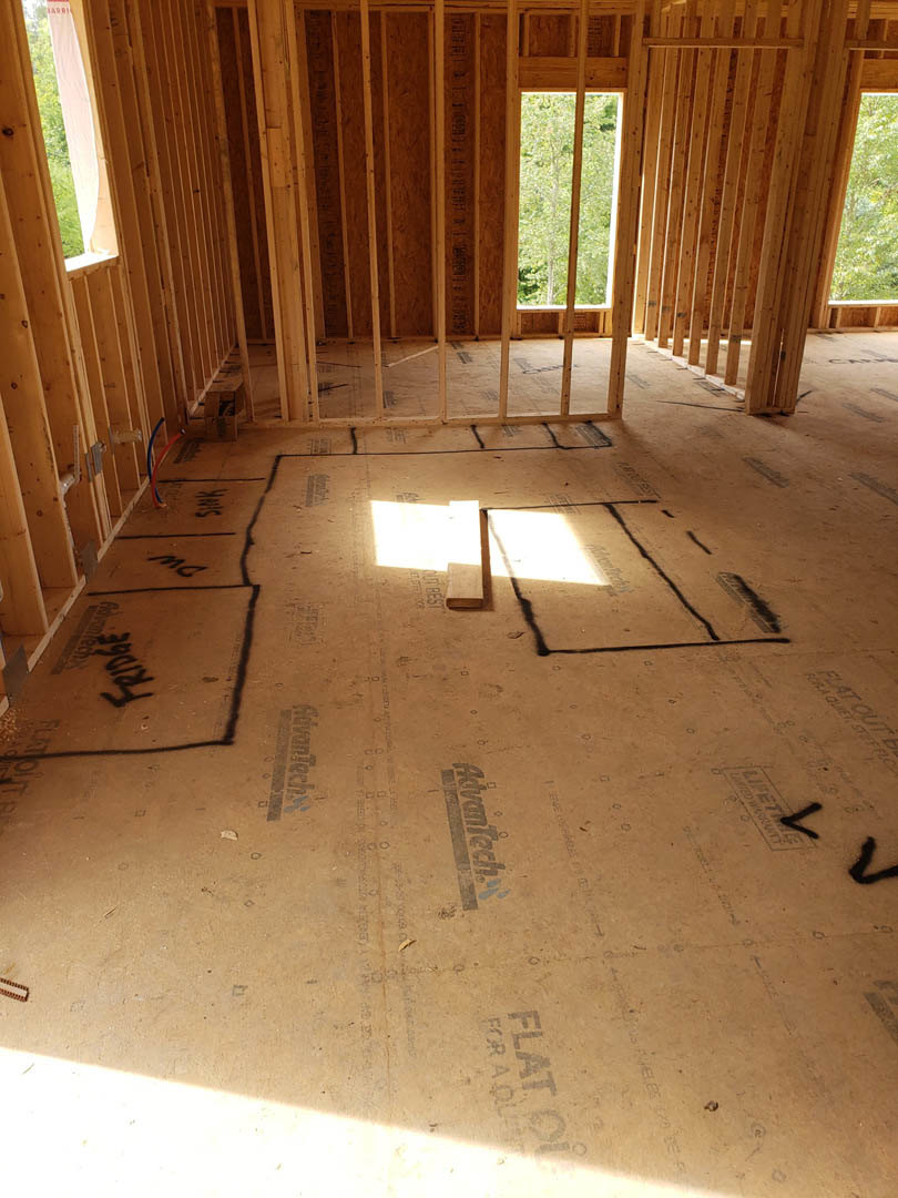 Unfinished room with exposed wood framing, large windows, and construction materials on subfloor