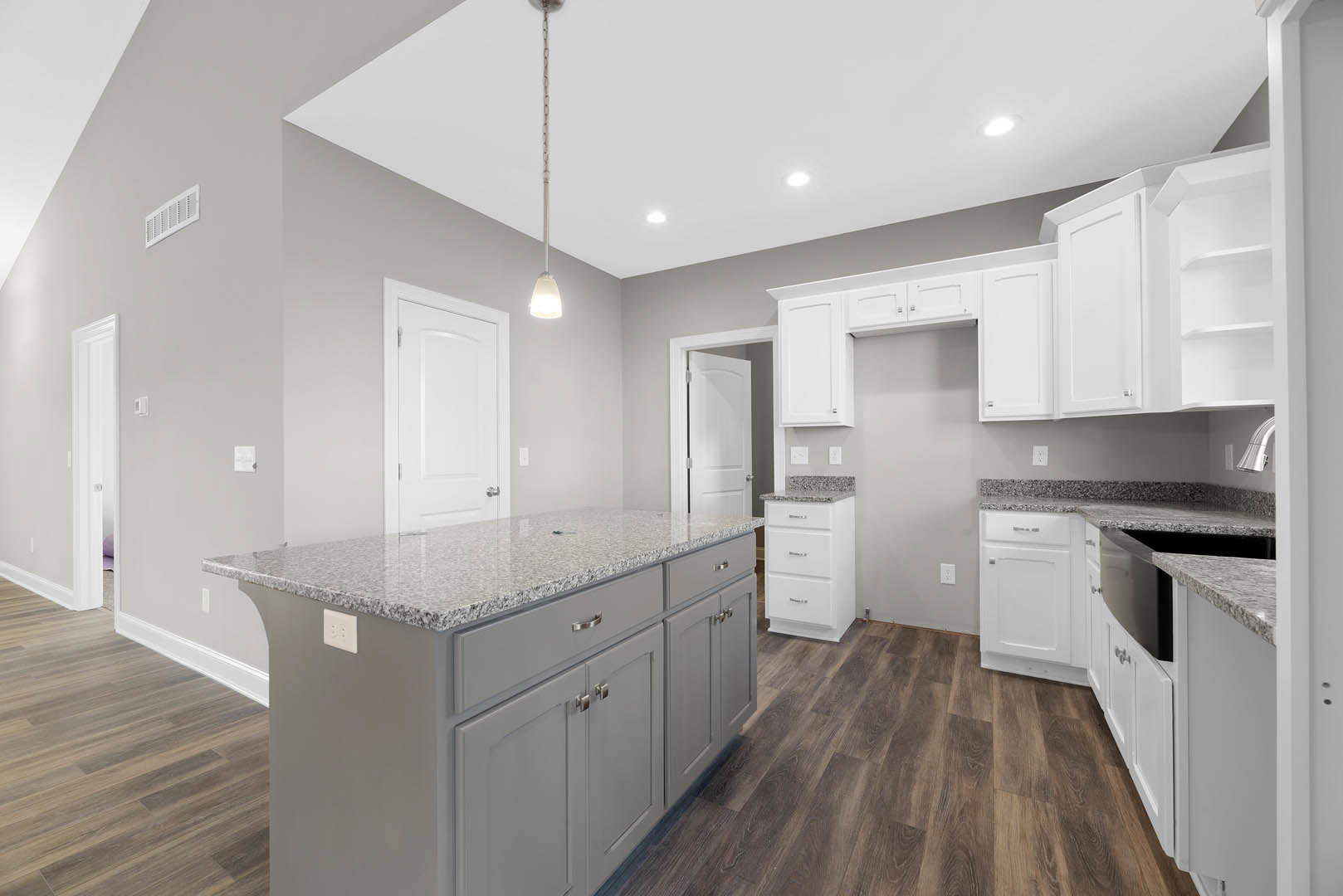 White kitchen cabinets with silver handles, granite countertops, stainless steel appliances, white vent on wall, light fixture above, and white door adjacent to cabinetry.