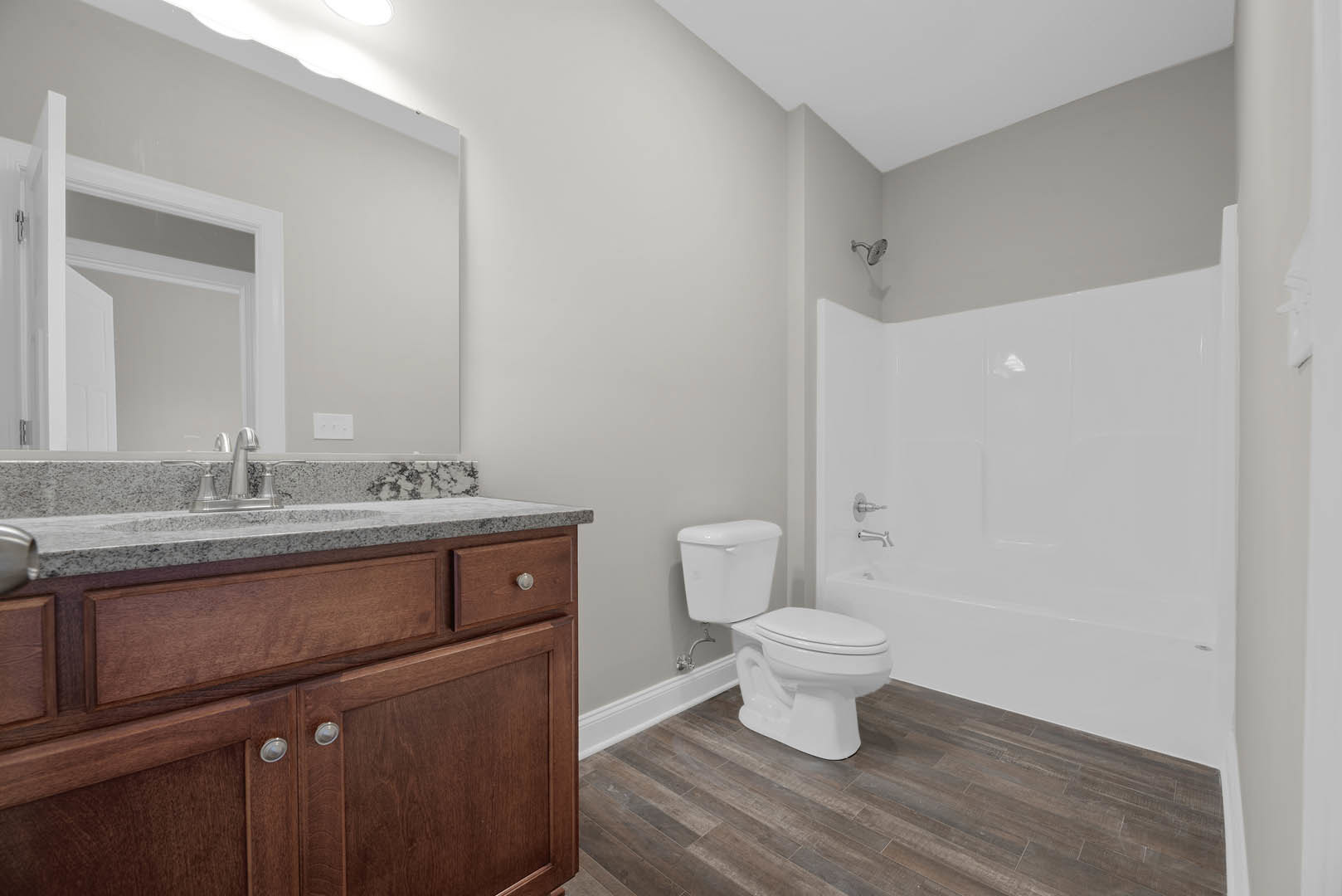 Modern bathroom featuring white tile walls, a sleek toilet, a rectangular sink with chrome faucet, light wood cabinetry, and an open white door leading into the room.