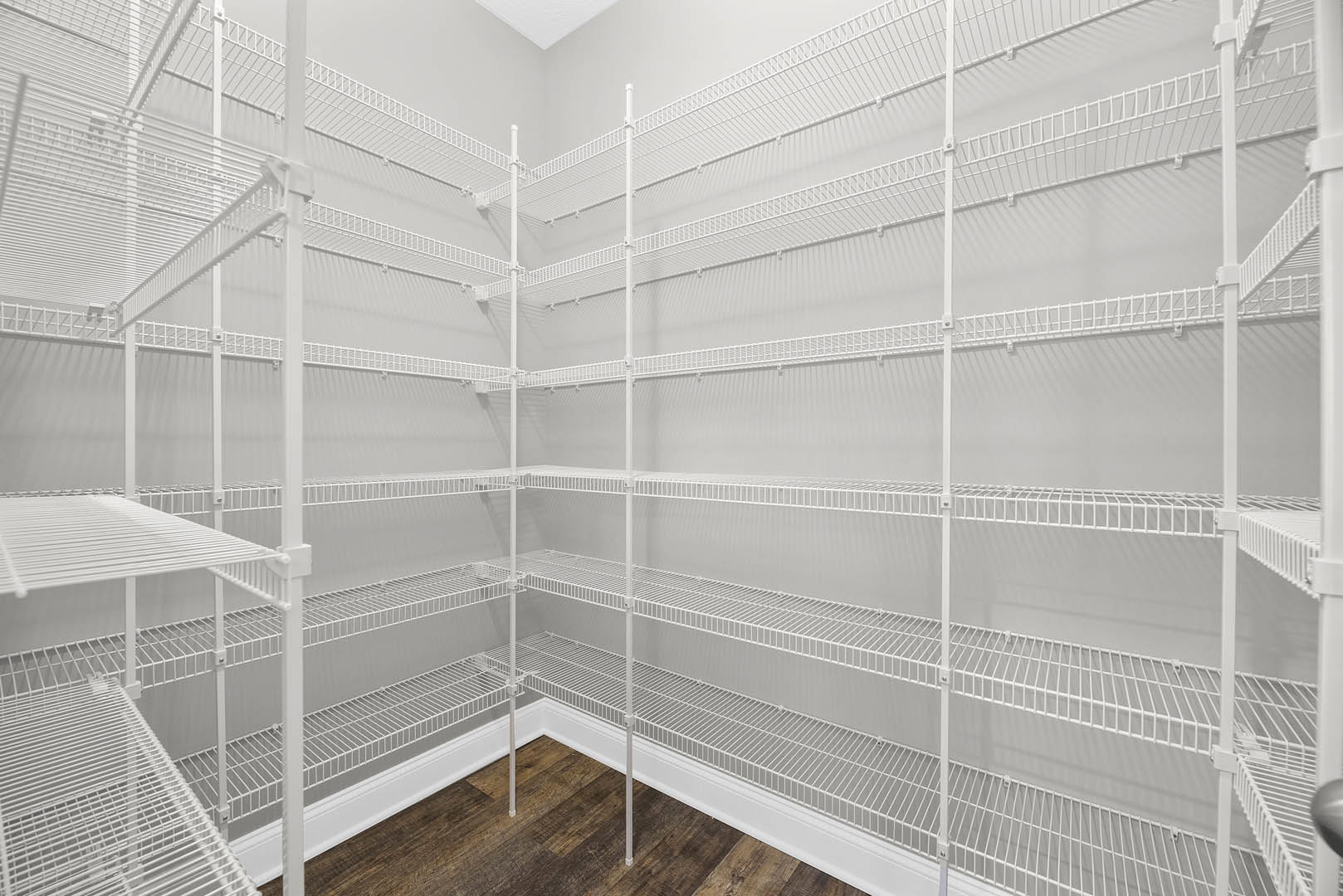 Spacious white pantry with multiple open shelves and metal support bars