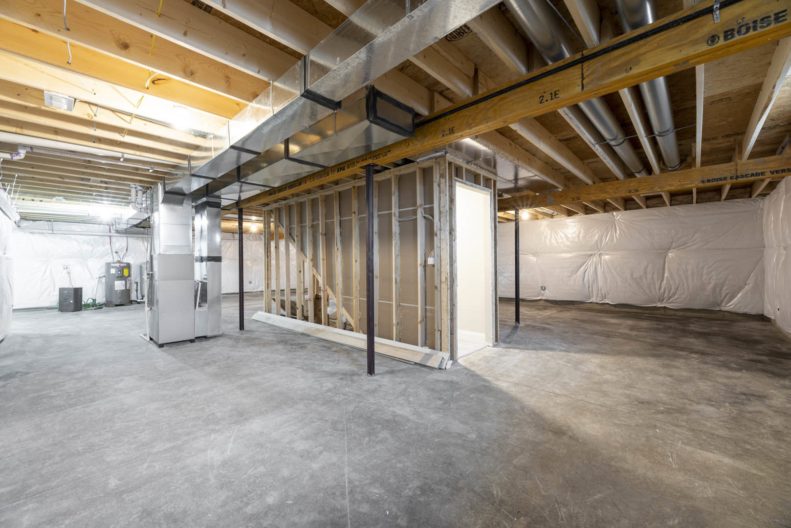 Concrete floor with exposed wood framing, white wall featuring a window frame, wooden shelf holding a white bag, metal and glass ventilator, black box with microphone, unfinished
