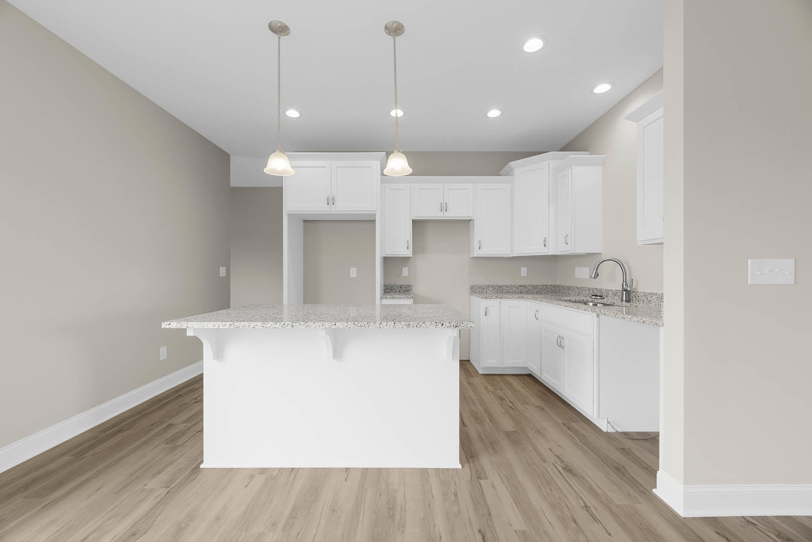 White kitchen cabinets with marble countertops, stainless steel faucet, pendant light fixture hanging from ceiling, tile backsplash, and light-colored flooring.