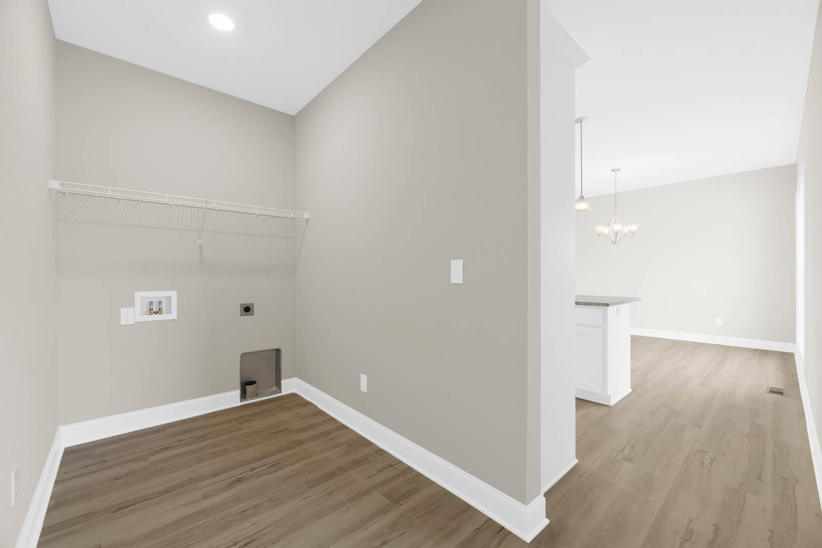 Wood flooring and white plaster walls in a modern room, featuring a white cabinet with silver handle, a white shelf holding two bottles, and a white metal railing on a white