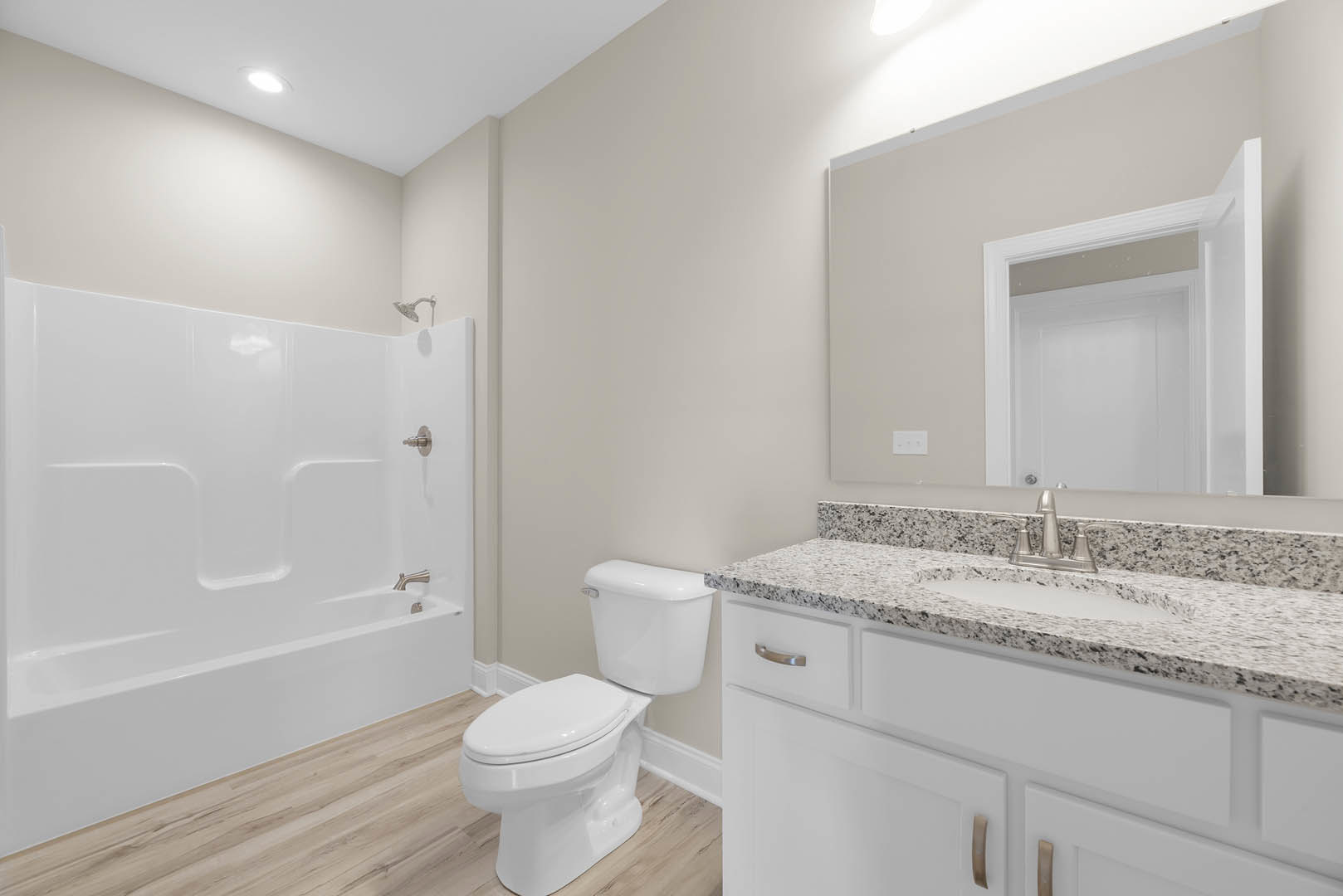 Bathroom with white toilet, white bathtub, granite countertop with silver faucet, tiled walls, and sink