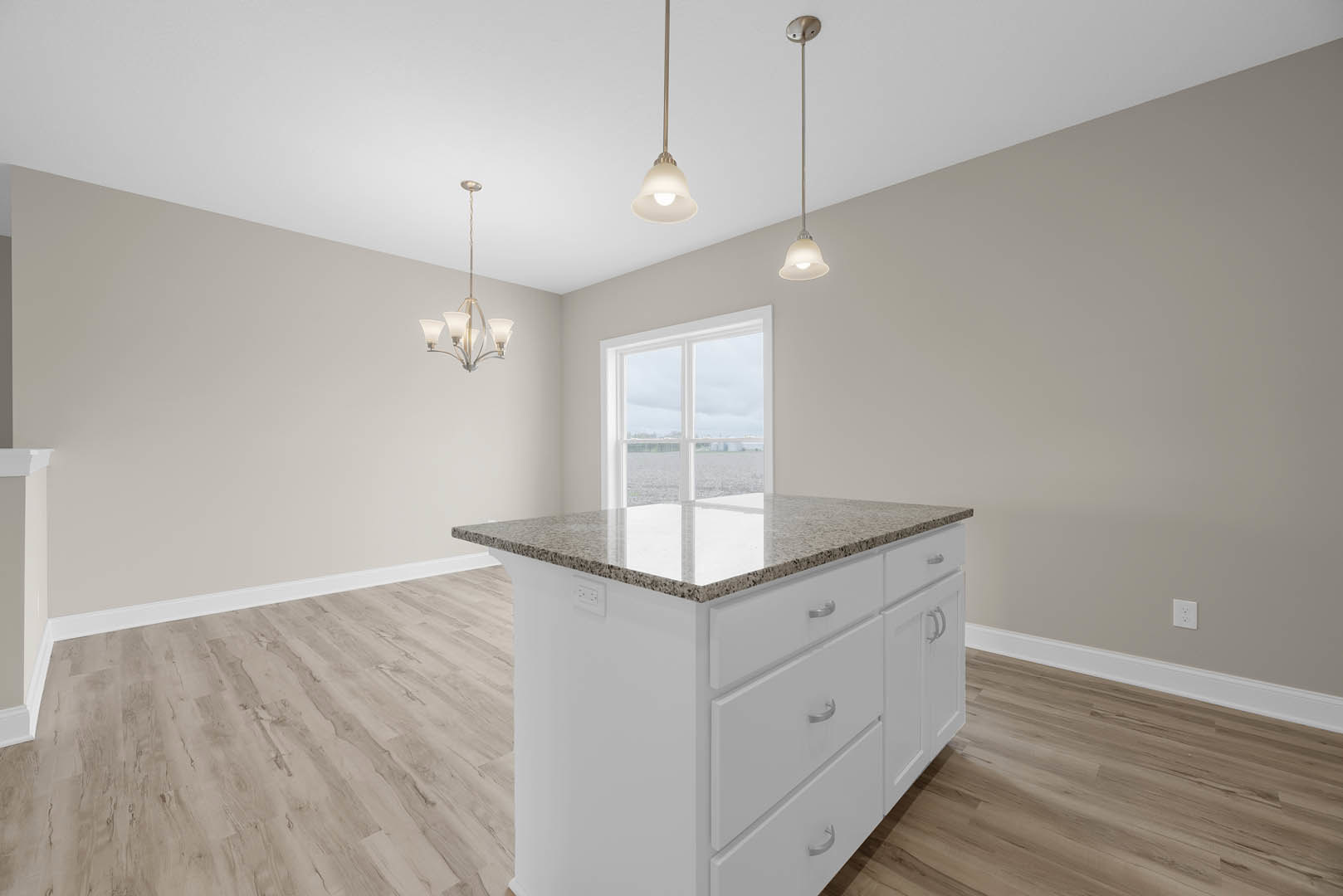 White kitchen island with drawers, quartz countertop, pendant light fixture overhead, large window with ocean view, hardwood flooring, white cabinetry