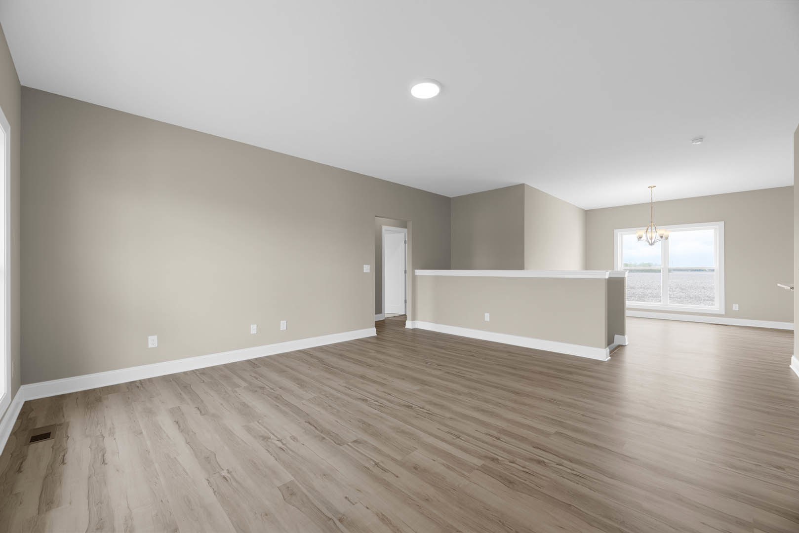 Hardwood floor room featuring a white countertop, large window, white walls with matching trim, ceiling light fixture, and a white door with metal frame