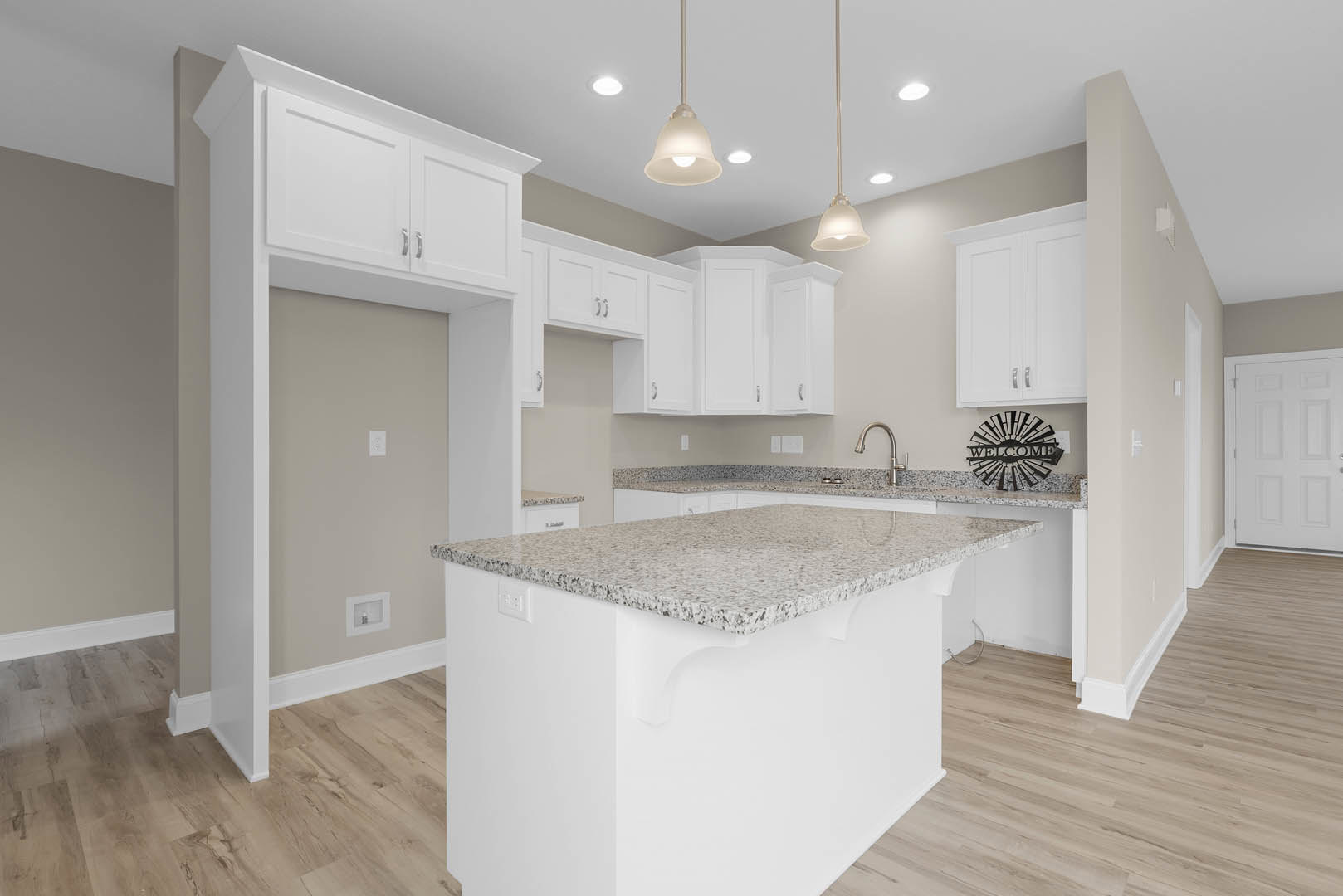 Marble kitchen island with waterfall edge, white cabinetry, tile backsplash, stainless steel sink, and light wood flooring