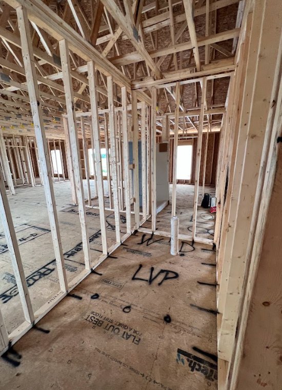 Exposed wood framing and beams with partially installed insulation inside a new home under construction