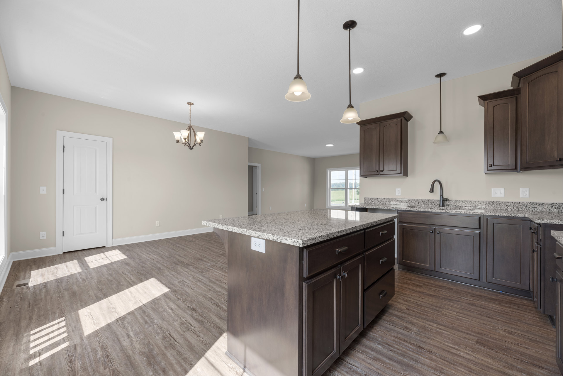 Marble kitchen island with waterfall edge, white cabinetry, black hardware, tile backsplash, pendant lighting, stainless steel sink, and wood flooring