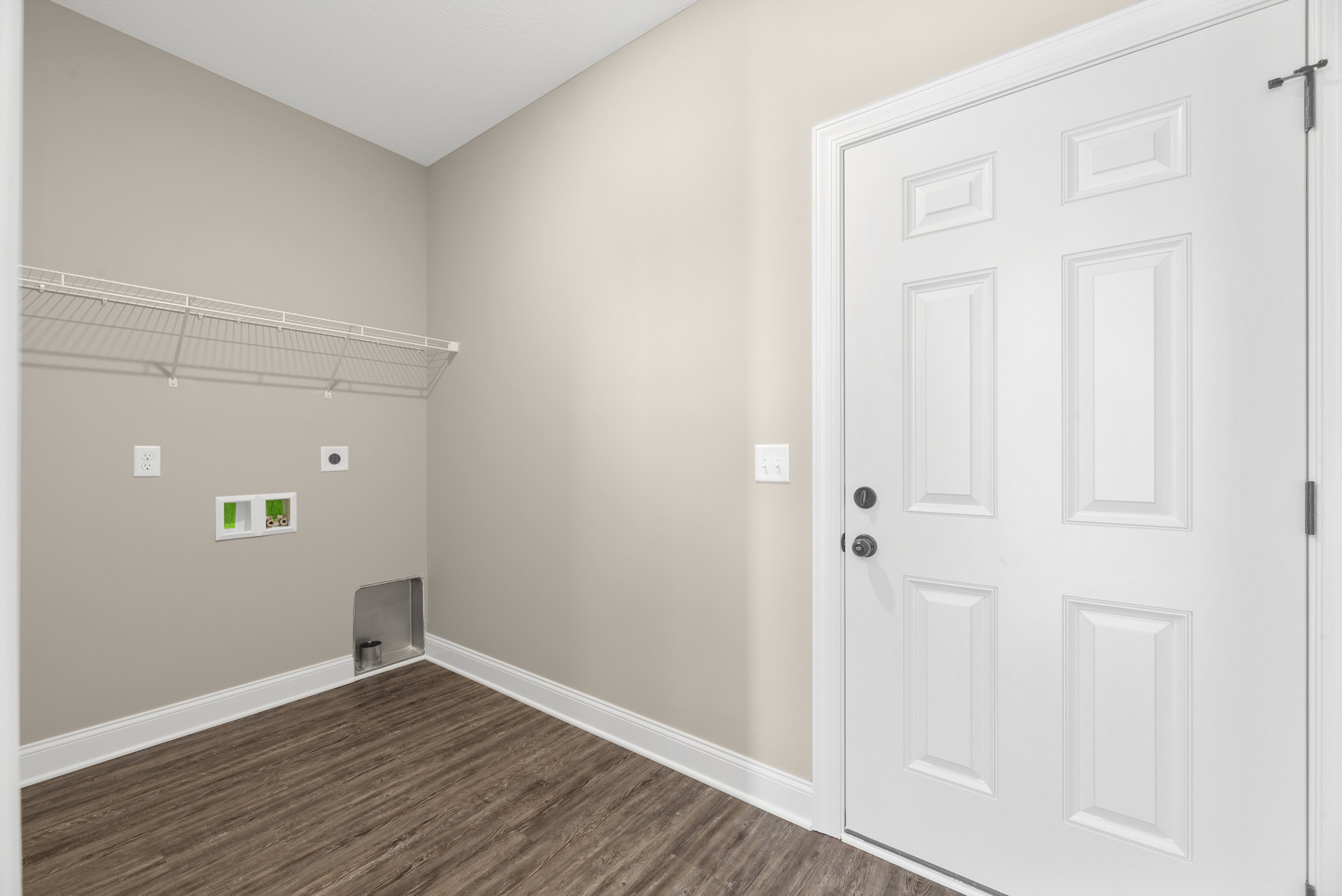 White paneled door with silver knobs set in a white frame, adjacent to a light switch on smooth plaster walls, wood flooring visible at the base.