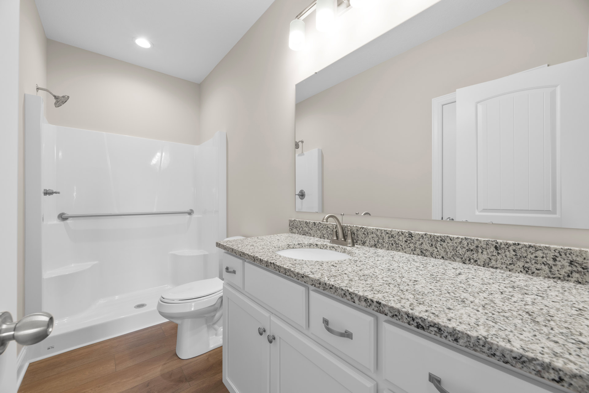 Bathroom with marble countertop, undermount sink, white toilet, glass shower enclosure, white cabinetry, tile flooring, and recessed ceiling light.