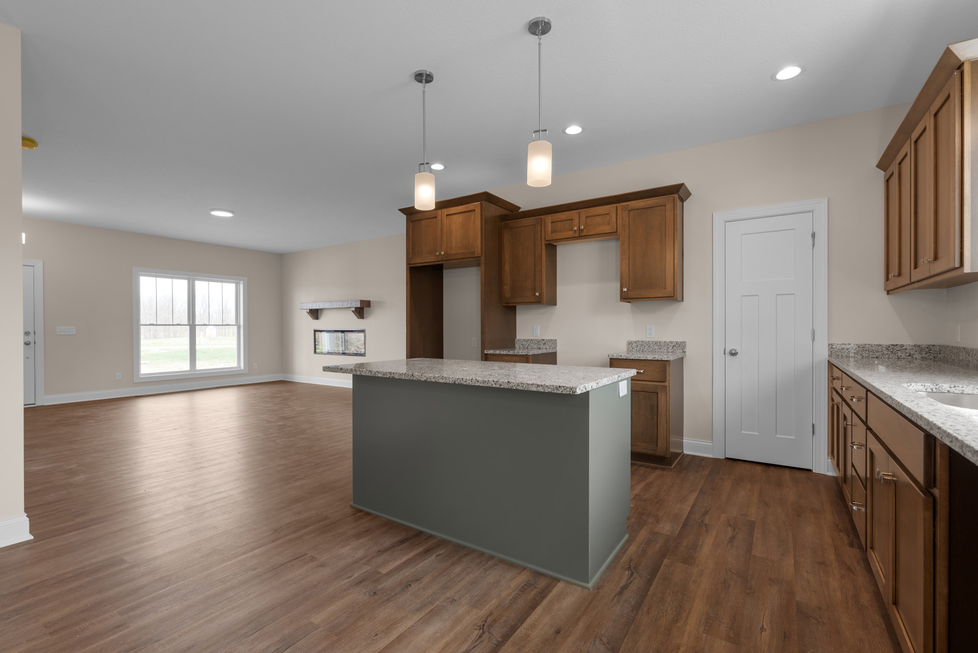 Kitchen with wood flooring, marble countertop, white cabinetry, stainless steel sink, close-up of a modern light fixture, white door with silver knob, window view of basketball