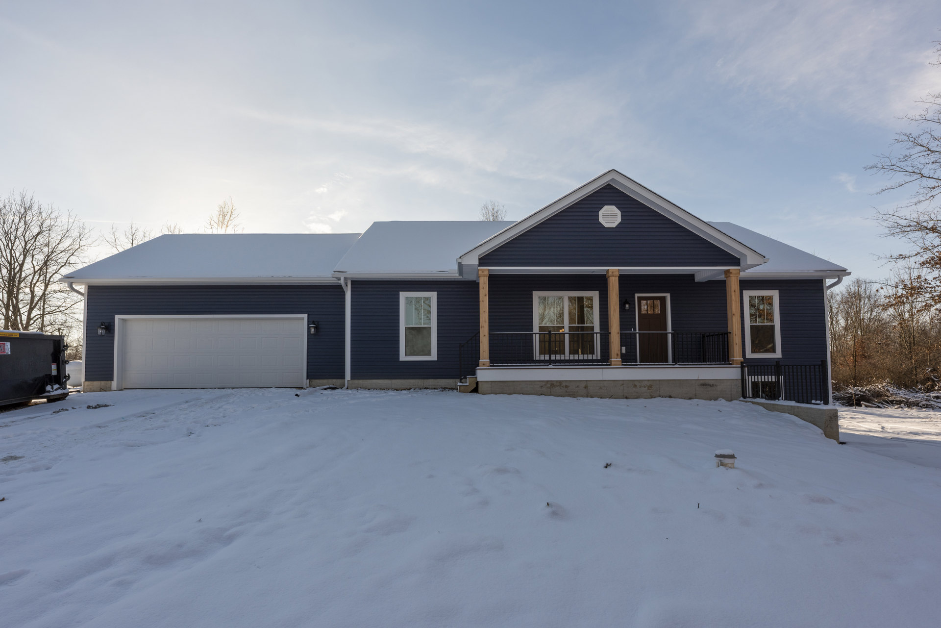 Two-story house with white siding, black window frames, and a dark front door, snow covering the ground and leafless tree in front yard