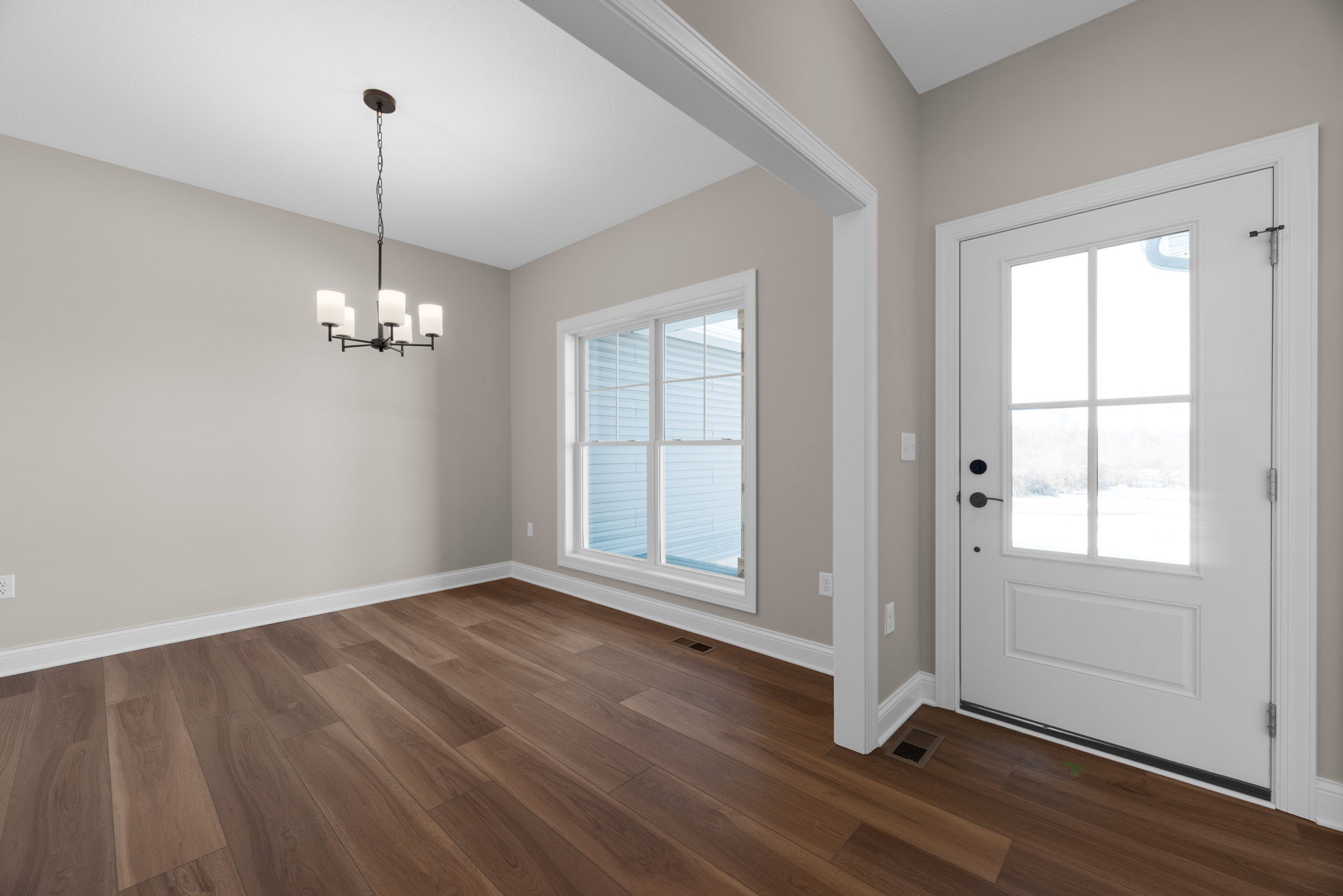 Hardwood floor room with white-trimmed window, white door featuring glass panes, and floor vent