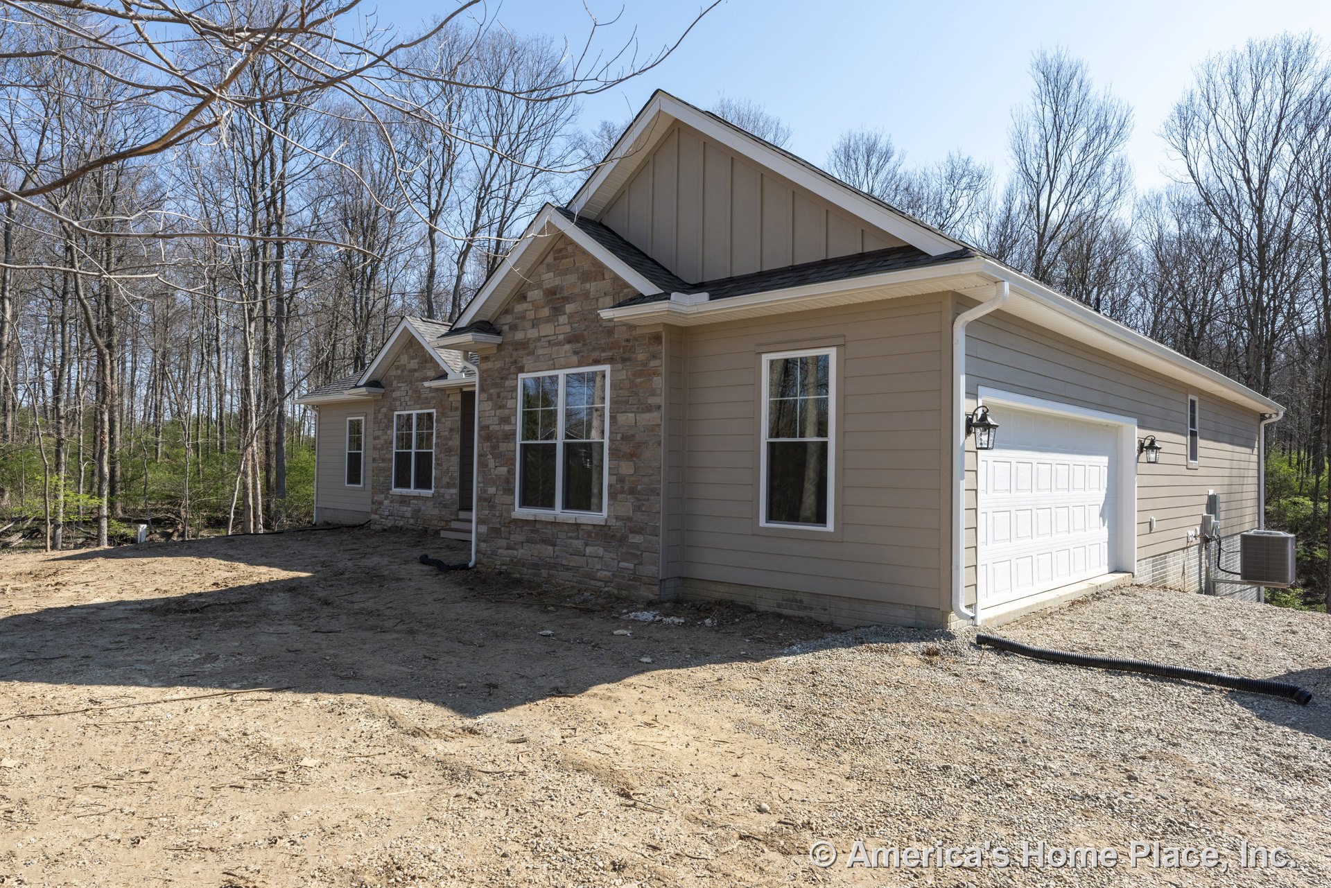 Stone veneer facade with horizontal lap siding, white framed windows, attached two-car garage, exterior wall lanterns, gable roof design, and prominent entry door with crisp trim