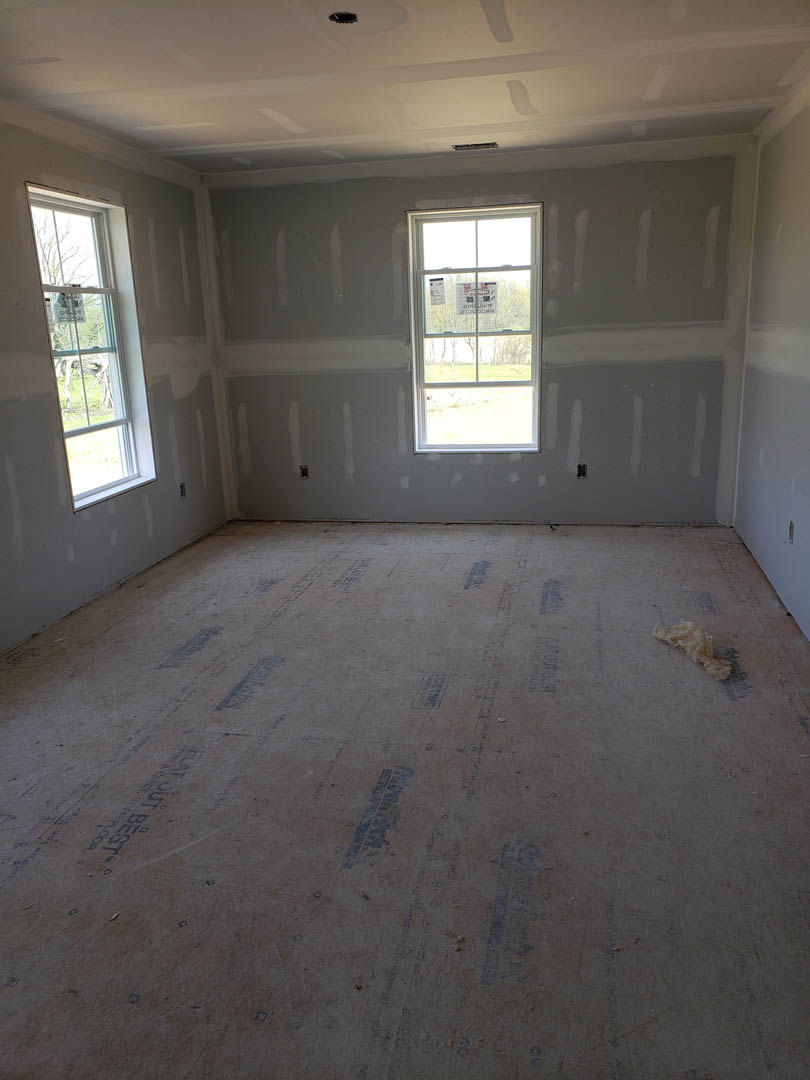 Bright room with white plaster walls, large window, light-colored flooring, and smooth ceiling