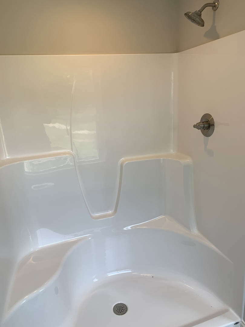 Freestanding white bathtub with silver faucet set against light tile wall in modern bathroom