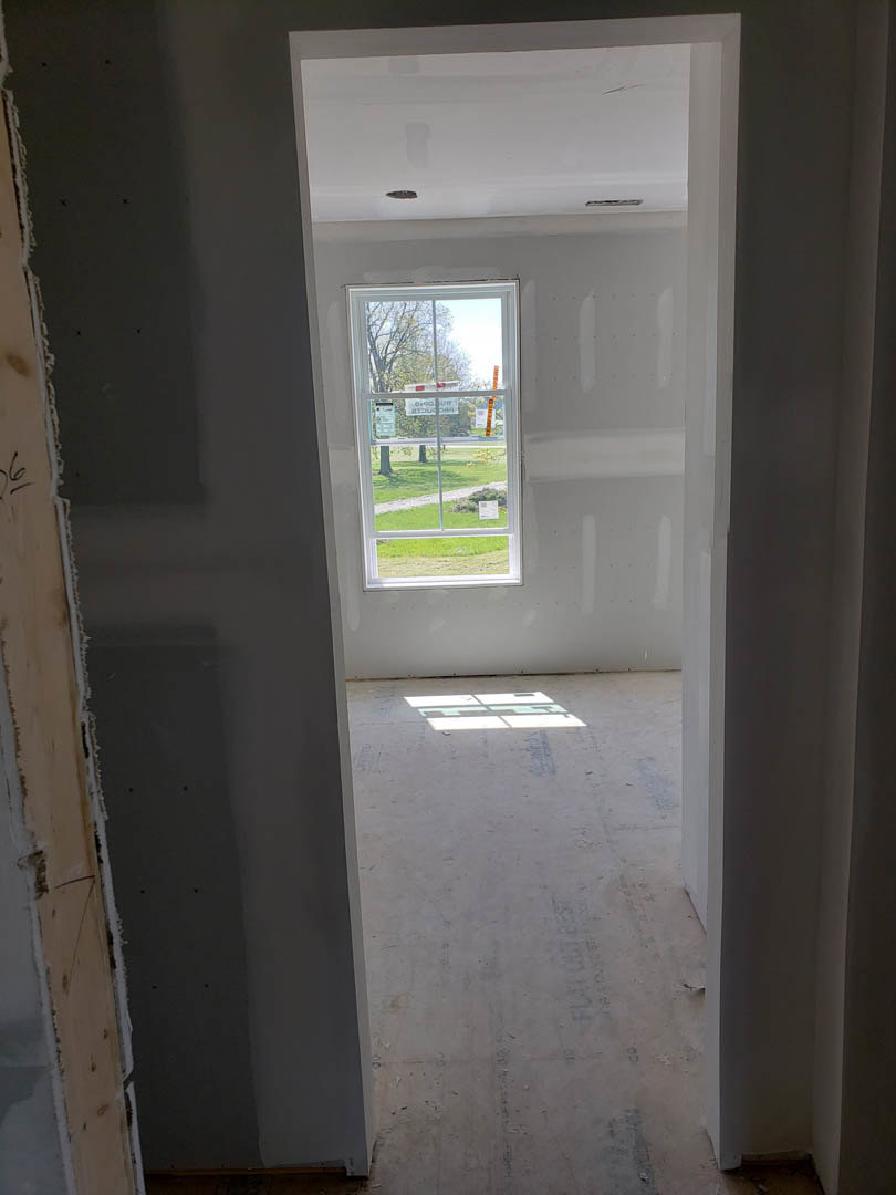 White plaster wall and window with attached sign, light wood flooring, interior residential space with daylighting.