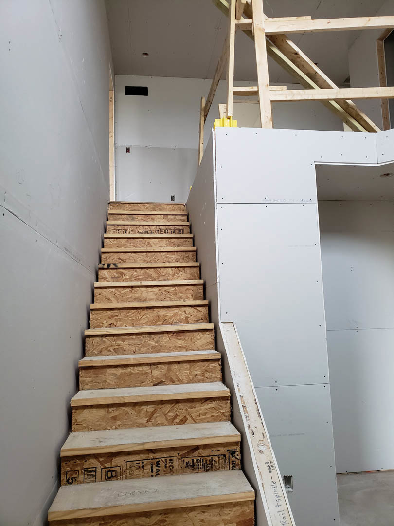 Wooden staircase with white risers and handrail, set against neutral walls in a modern residential interior.