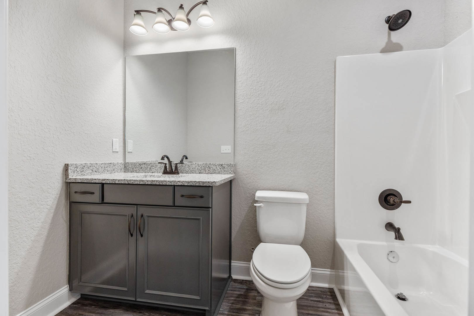White bathroom with rectangular sink, chrome faucet, wall-mounted mirror, toilet, and beige tile walls