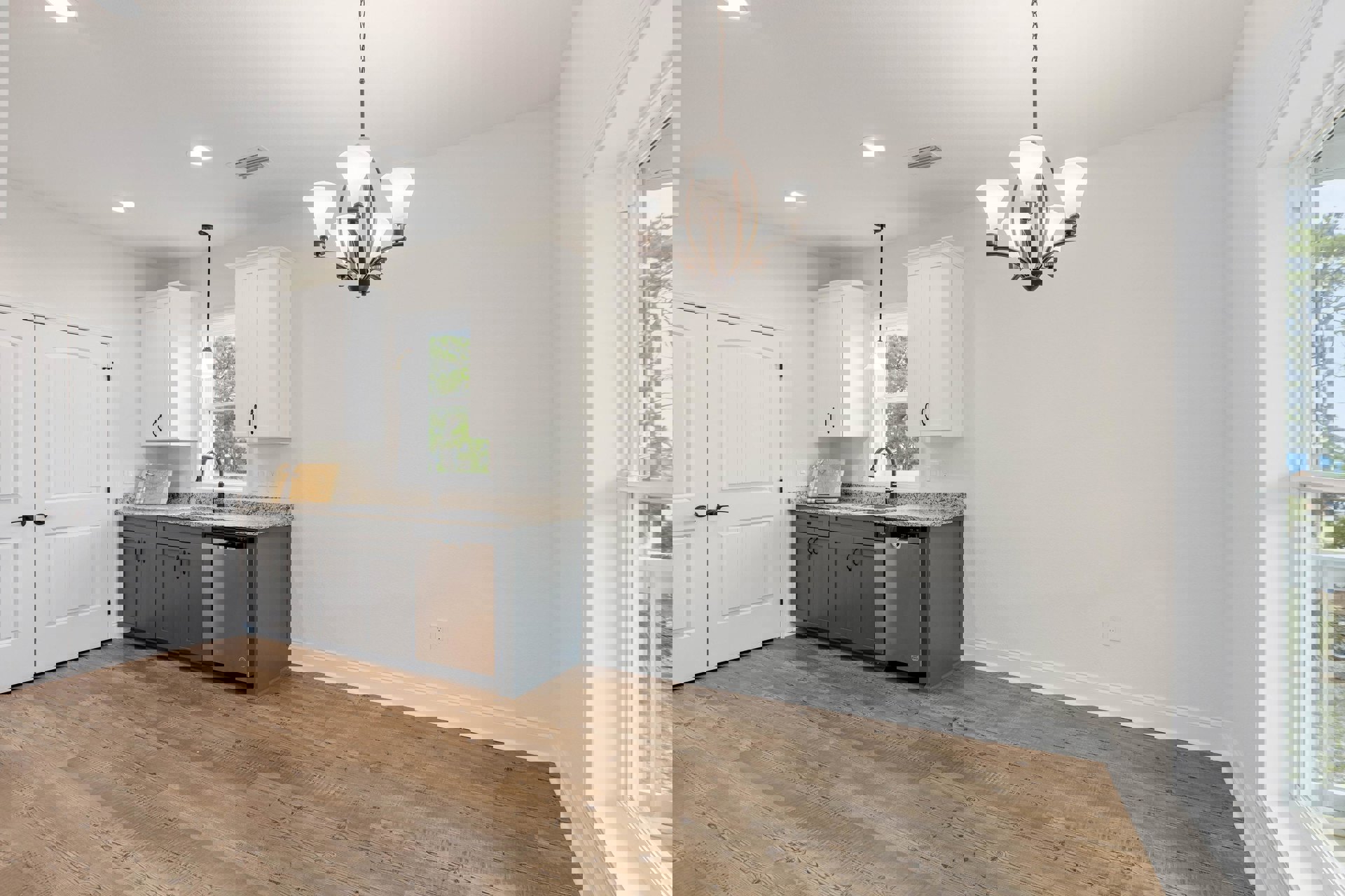 Kitchen with wood flooring, gray cabinets, white walls, silver refrigerator, sink with faucet, chandelier overhead, and white double doors with black handles