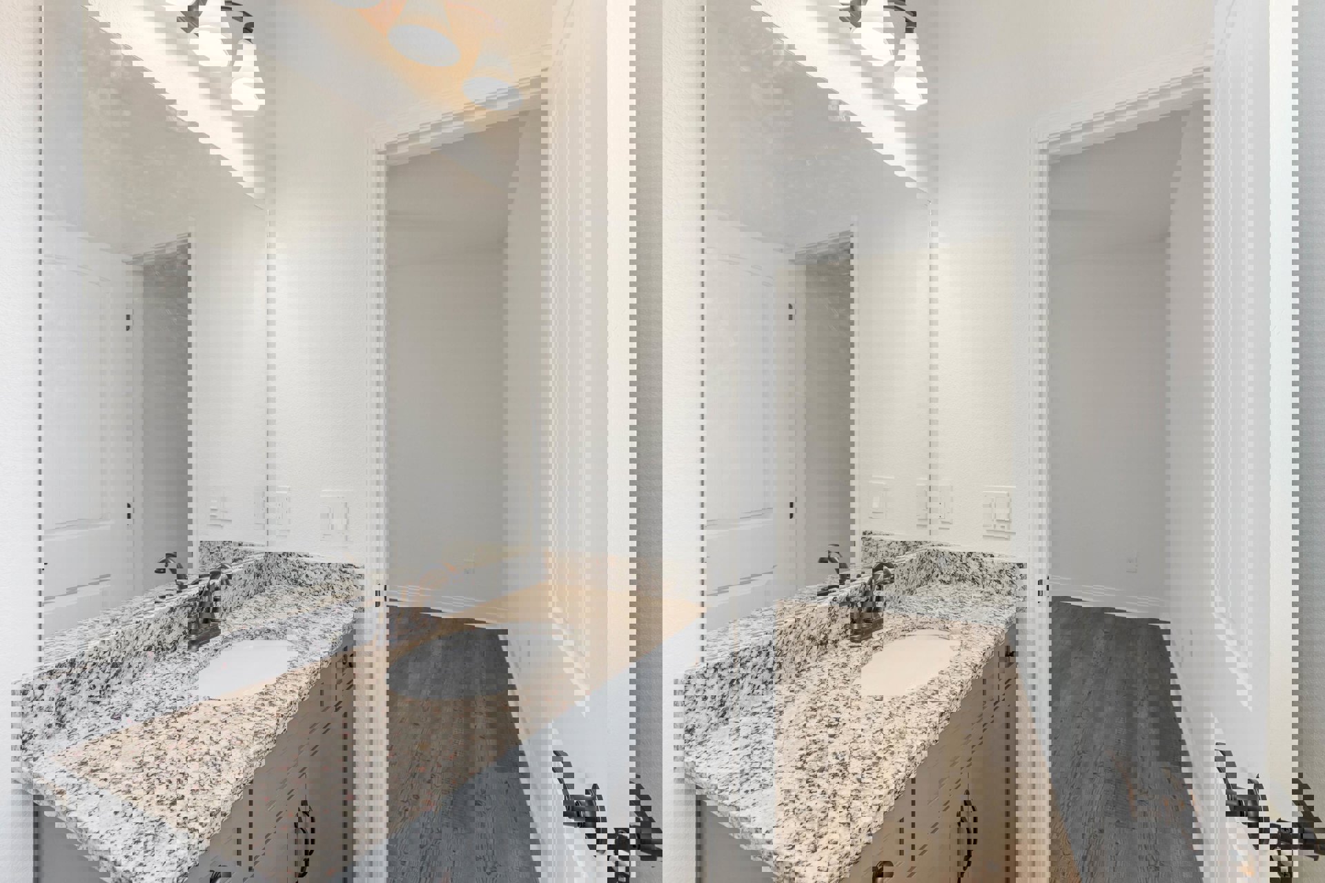 Marble countertop with undermount sink, wood plank flooring, wall-mounted mirror, chrome faucet, and neutral tile accents in bathroom