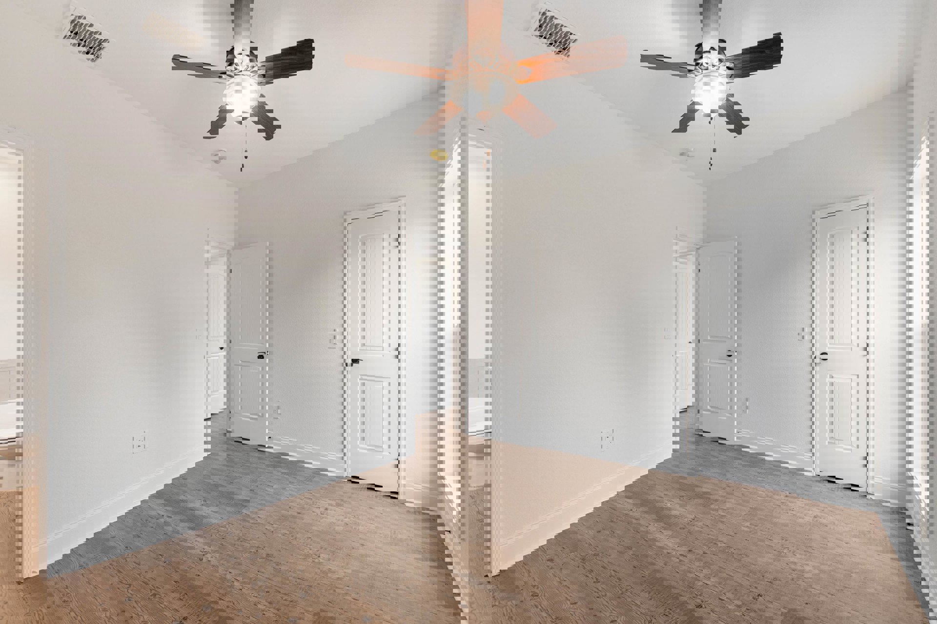 White walls, wood flooring, ceiling fan with light fixture, white door featuring black handle