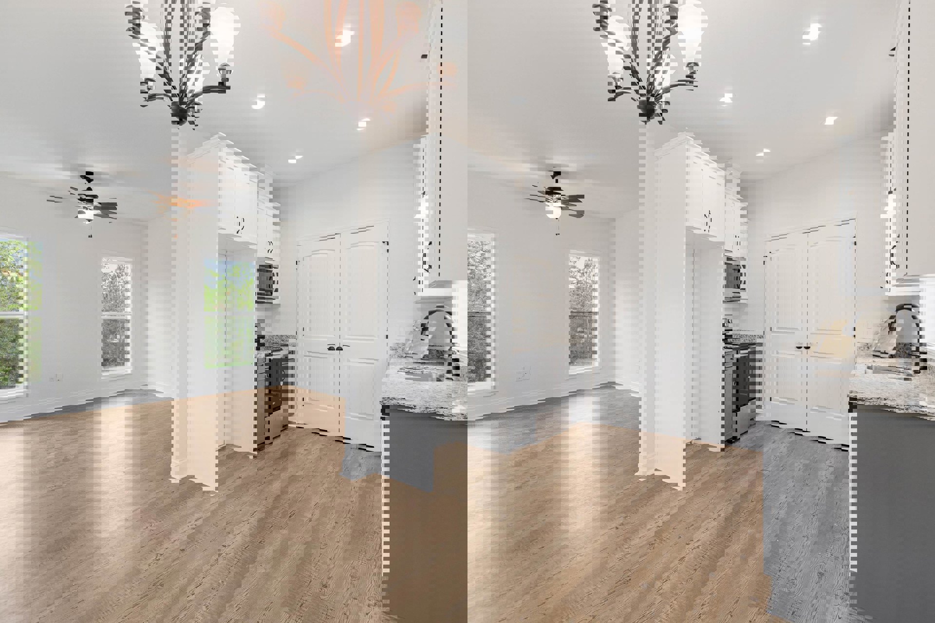 Open kitchen and dining area with wood flooring, white walls, cabinetry, double doors with black knobs, modern microwave oven, large window overlooking trees, and decorative