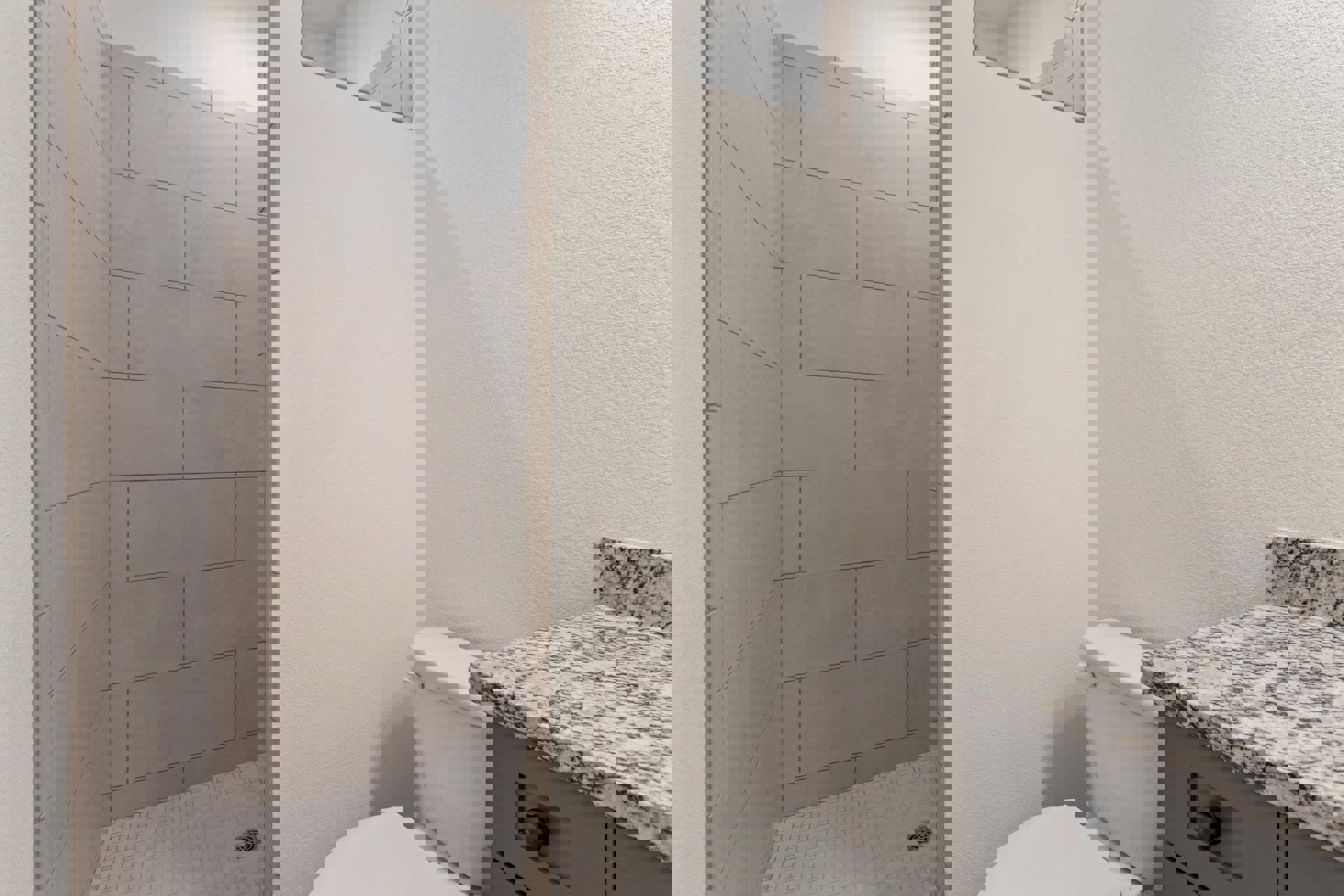 Bathroom with white toilet, glass-enclosed shower, black and white marbled countertop, white walls with trim, modern cabinetry and chrome fixtures