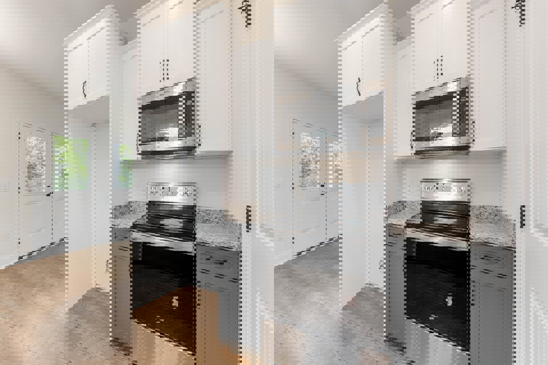 White kitchen cabinets with a built-in microwave above a black and silver oven, white door with matching trim, window overlooking trees, light countertops, and upper cupboards.