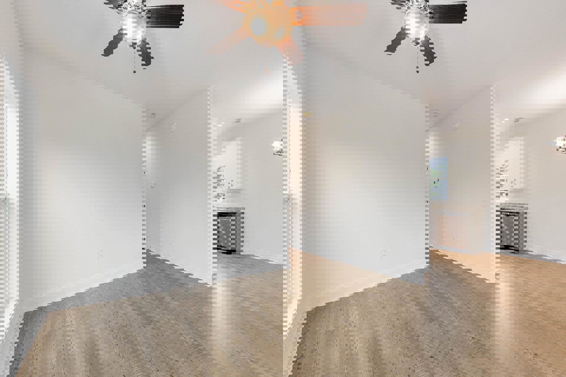 Ceiling fan with light fixture above wood flooring, white walls, white cabinet with black handles, dishwasher under counter, and white door with open window