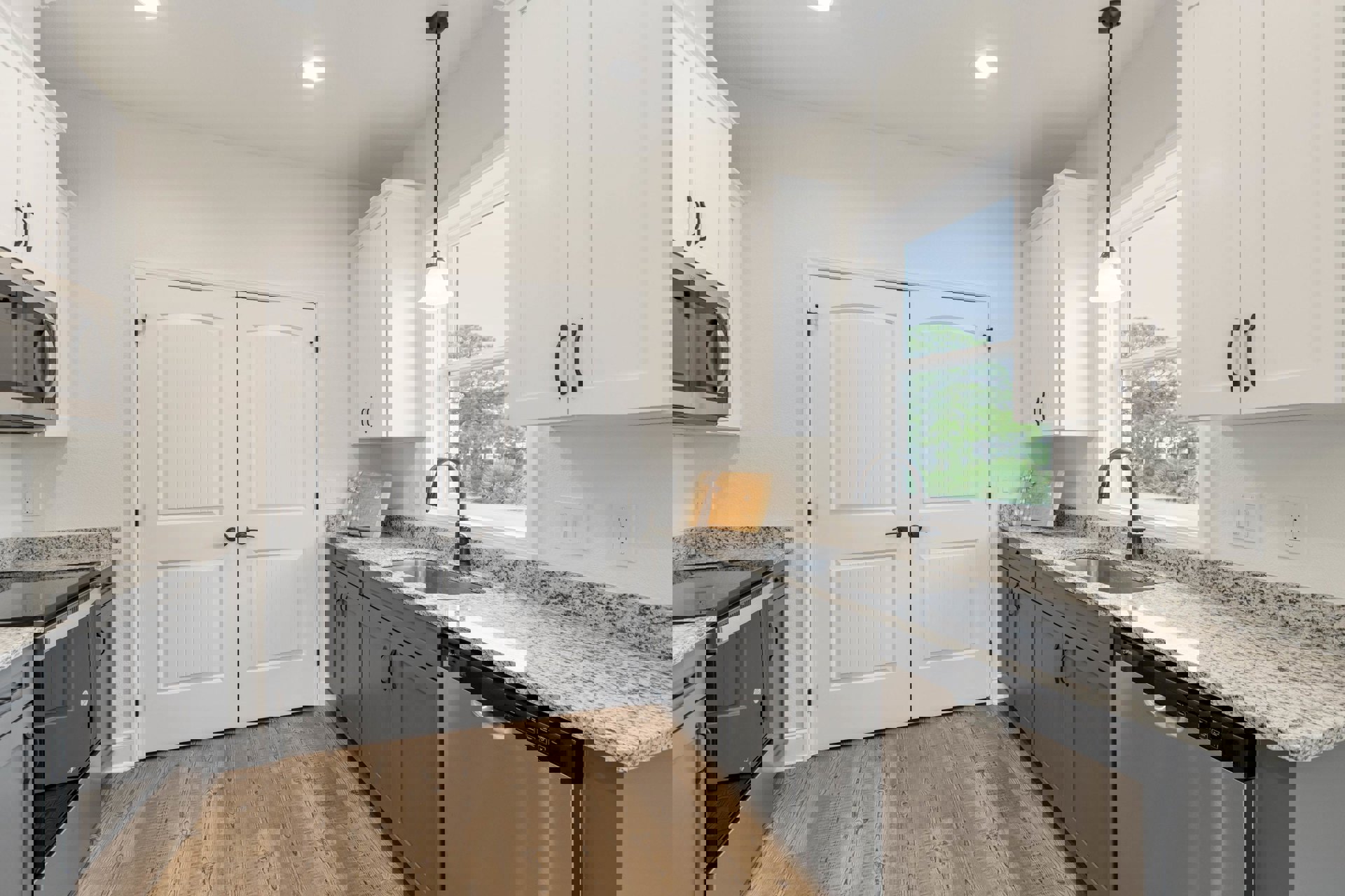 White kitchen cabinets with granite countertops, stainless steel sink, tile backsplash, recessed ceiling light, double white doors with black handles, wooden cutting board with