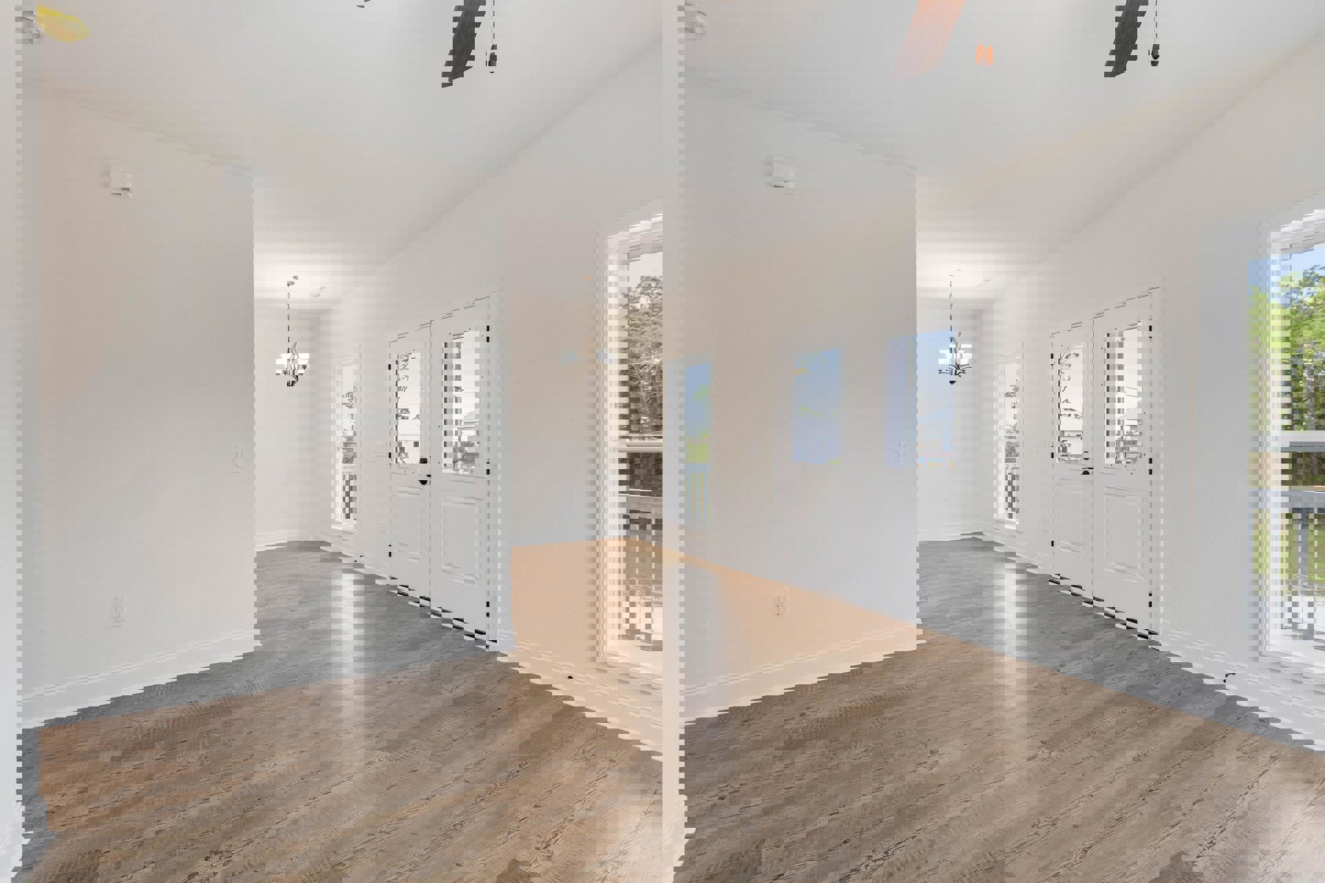 White-walled room with wood flooring, white double doors with glass panes, a window showing trees outside, and a chandelier with white shades.