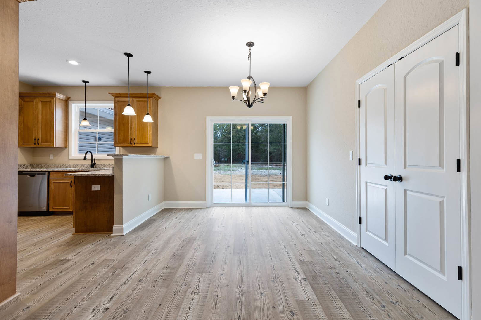 Hardwood floor kitchen with white cabinetry, black hardware, glass door opening to yard, double doors, and modern chandelier
