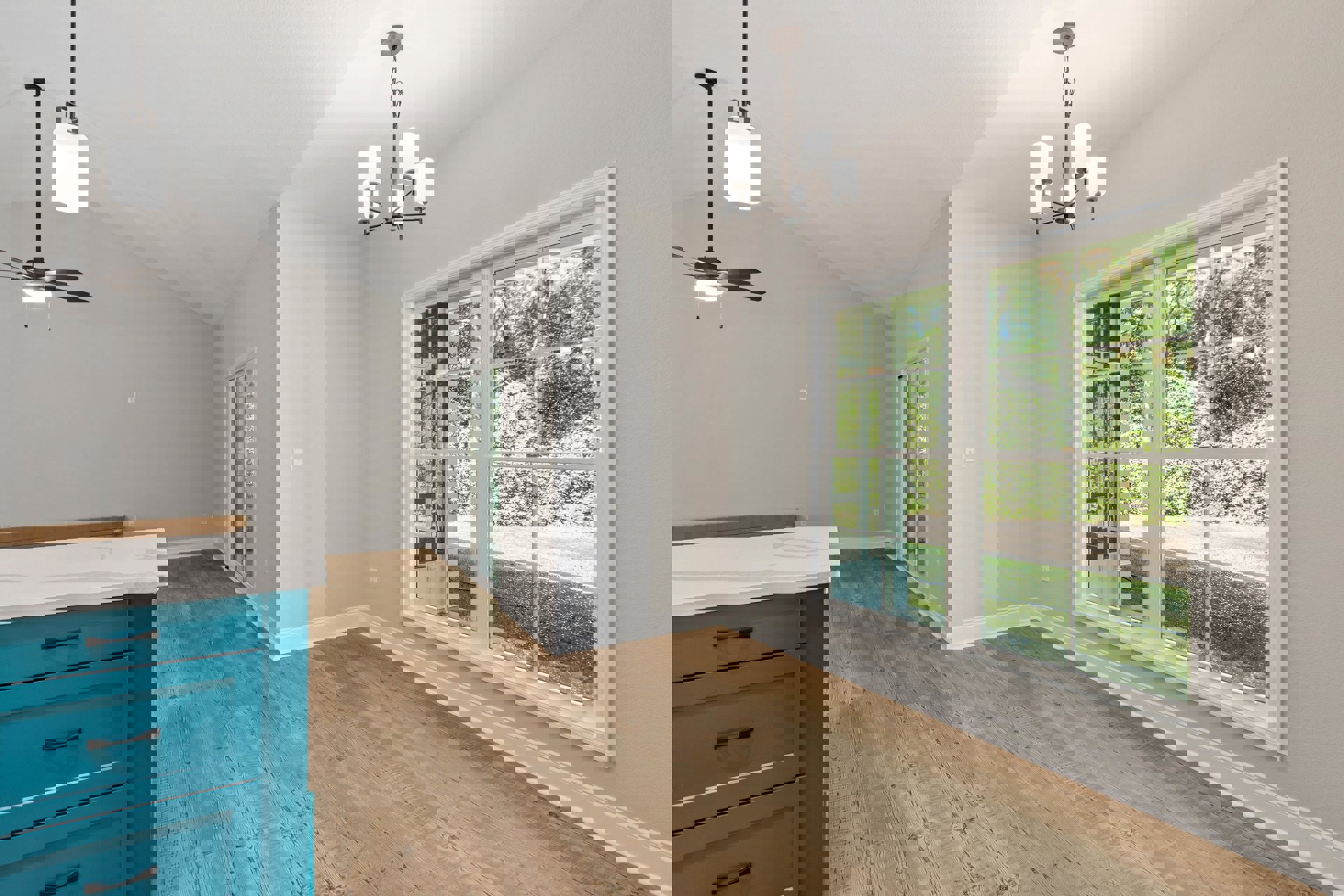 Open kitchen with blue island featuring black handles, wood flooring, white ceiling with recessed lighting and ceiling fan, large window overlooking trees, white walls, and modern