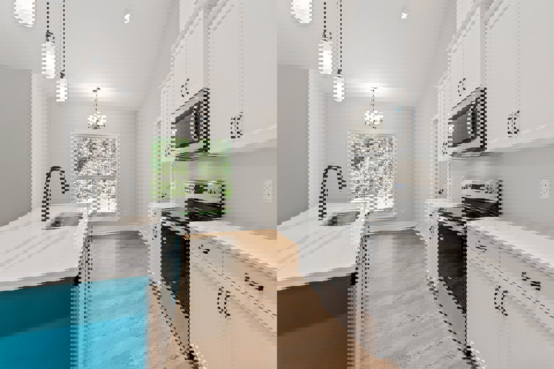 White kitchen cabinets, black stove, stainless sink under windows, white countertop, built-in microwave, electrical outlet, curved white light fixture